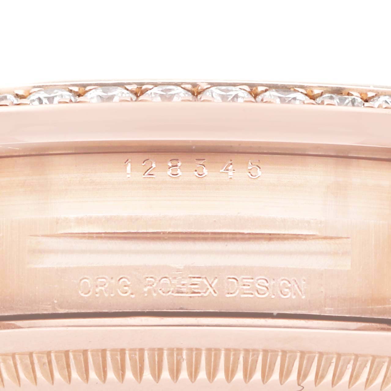 The image shows a close-up of the bezel edge and part of the case with engravings on a Rolex President 128345 Men
s Rose Gold Brown Dial watch.