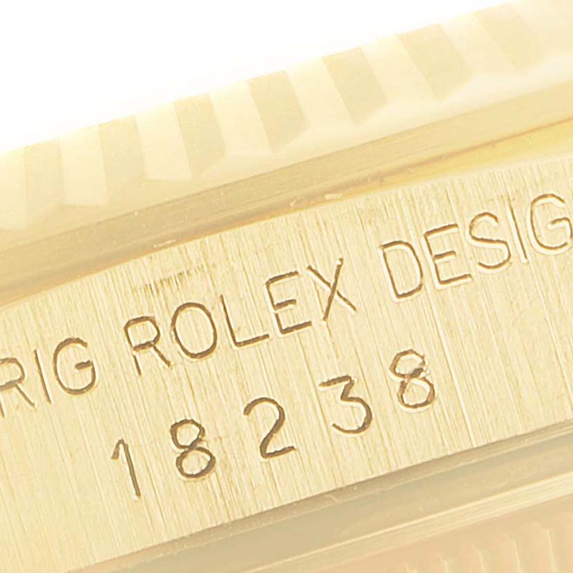 The image shows an engraving on the side case of a Rolex President 18238 Men
s Yellow Gold Champagne Dial model with visible fluting detail.