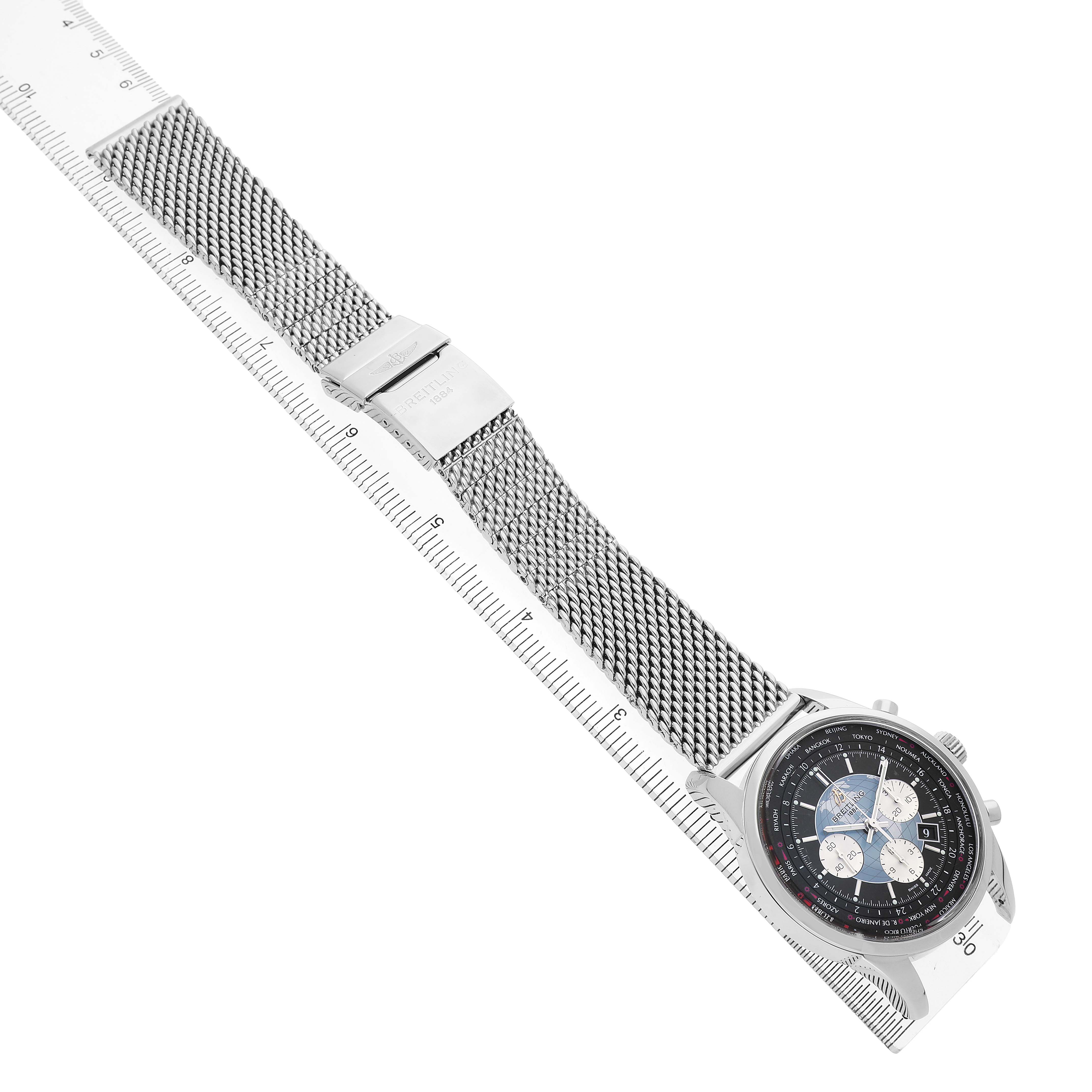The Breitling Transocean AB0510 Men's Stainless Steel Black Dial is shown in an angled overhead shot, highlighting its mesh bracelet and detailed face beside a ruler.