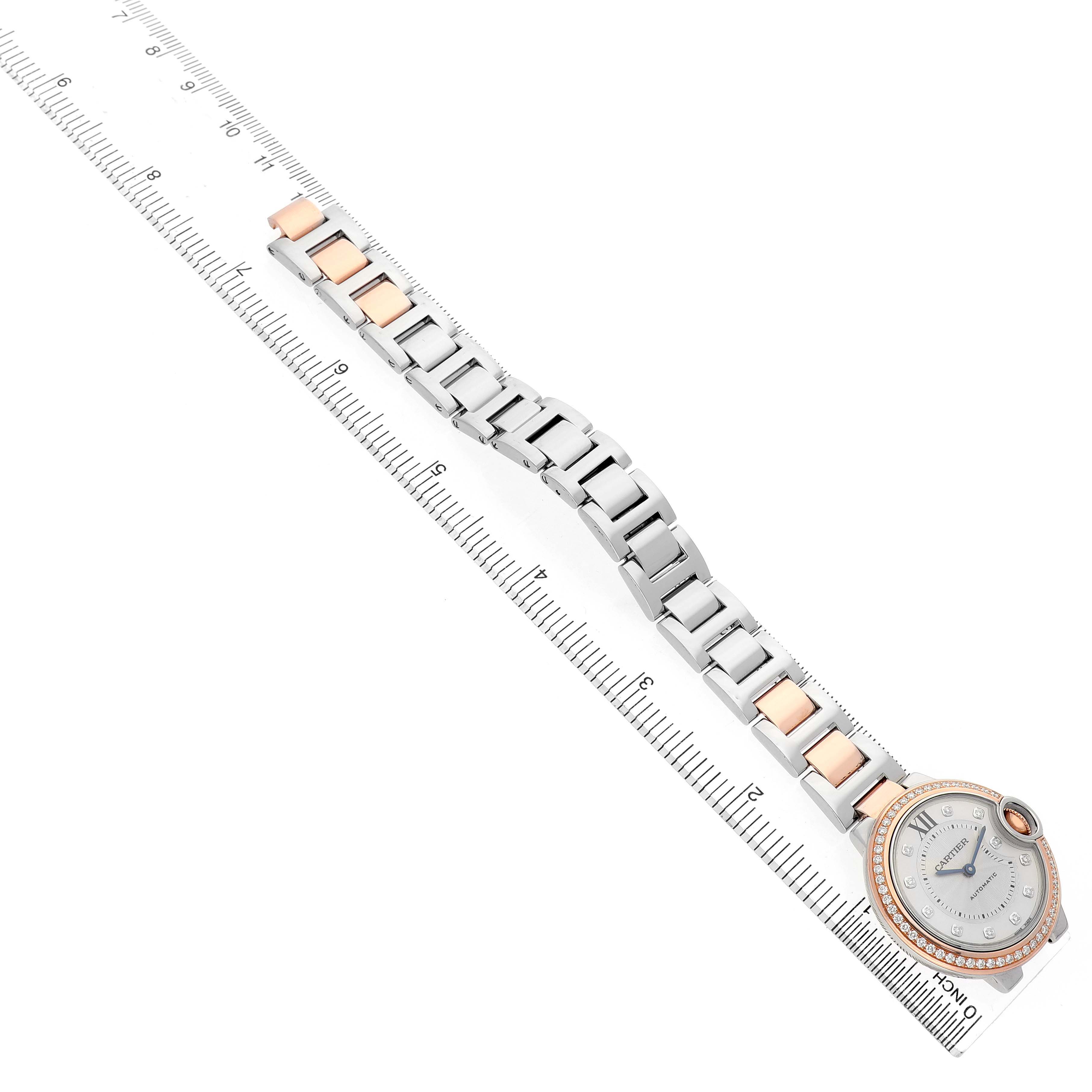 The Cartier Ballon Bleu WE902077 Women's Steel and Gold (two tone) Silver Dial watch is displayed diagonally, showcasing the watch face and full bracelet alongside a ruler for scale.