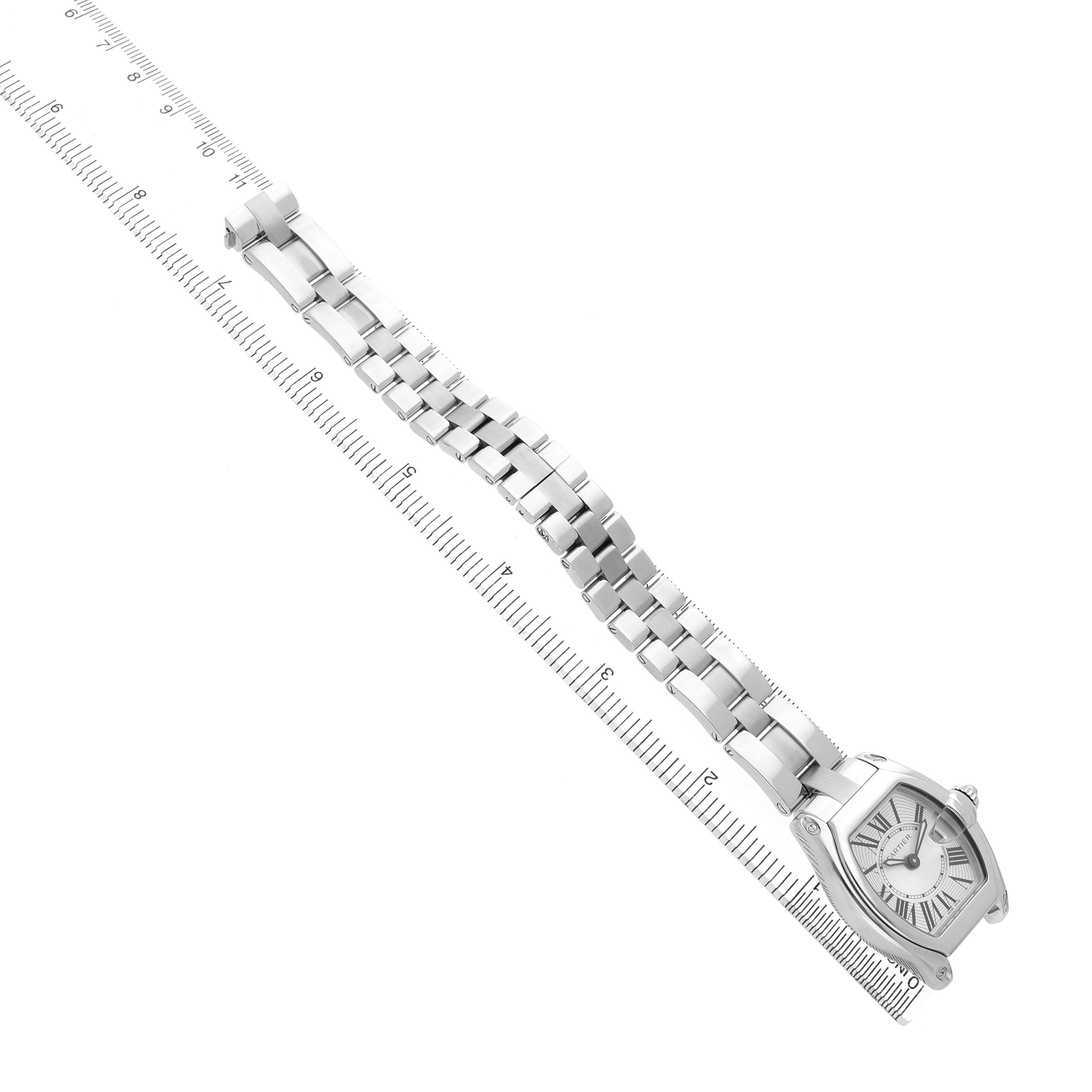 The Cartier Roadster W62016V3 Women's Stainless Steel Silver Dial watch is shown from an angled perspective, highlighting its face and full metal bracelet alongside a ruler.