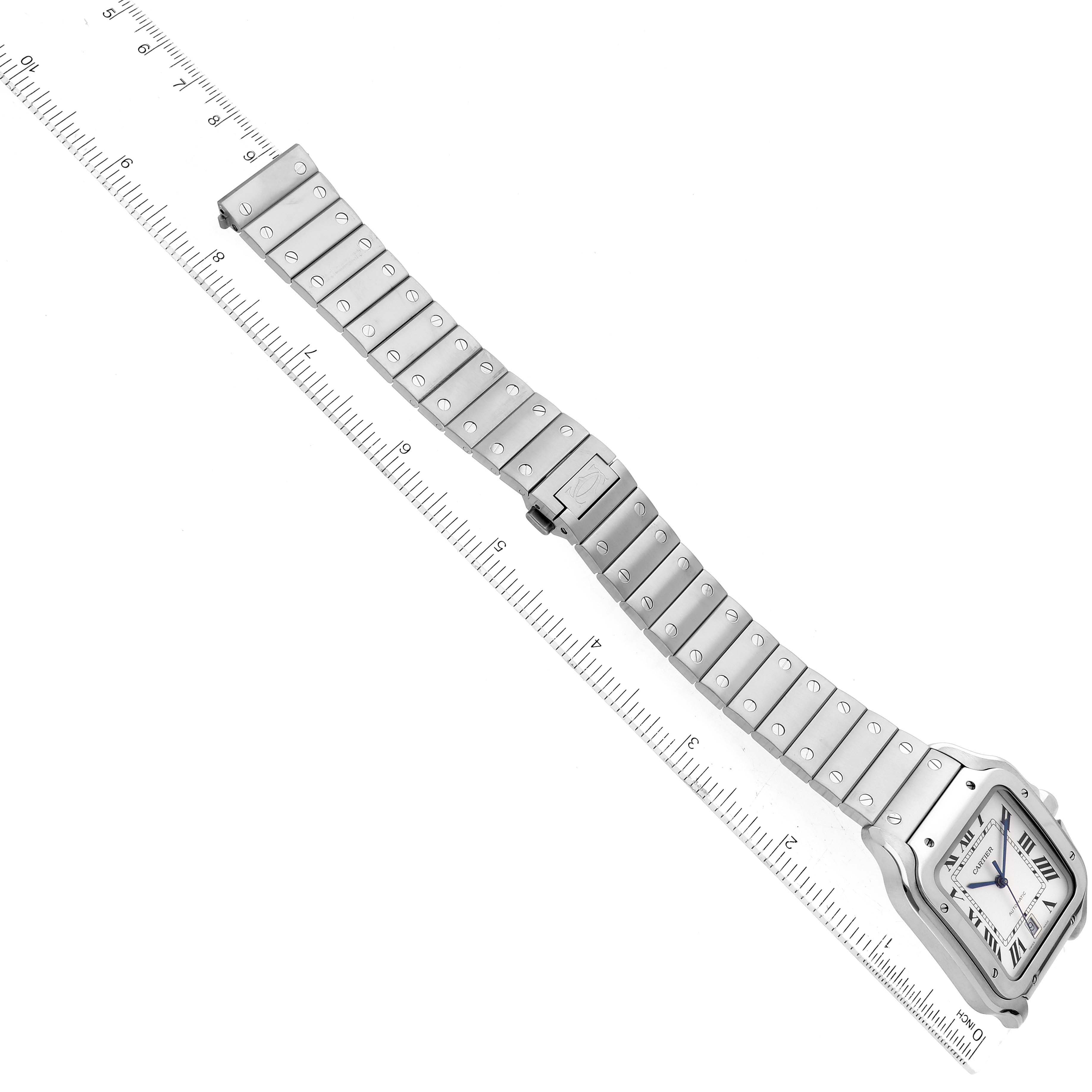 The image shows a Santos model watch by Cartier, featuring its face and metal bracelet, angled diagonally over a ruler.