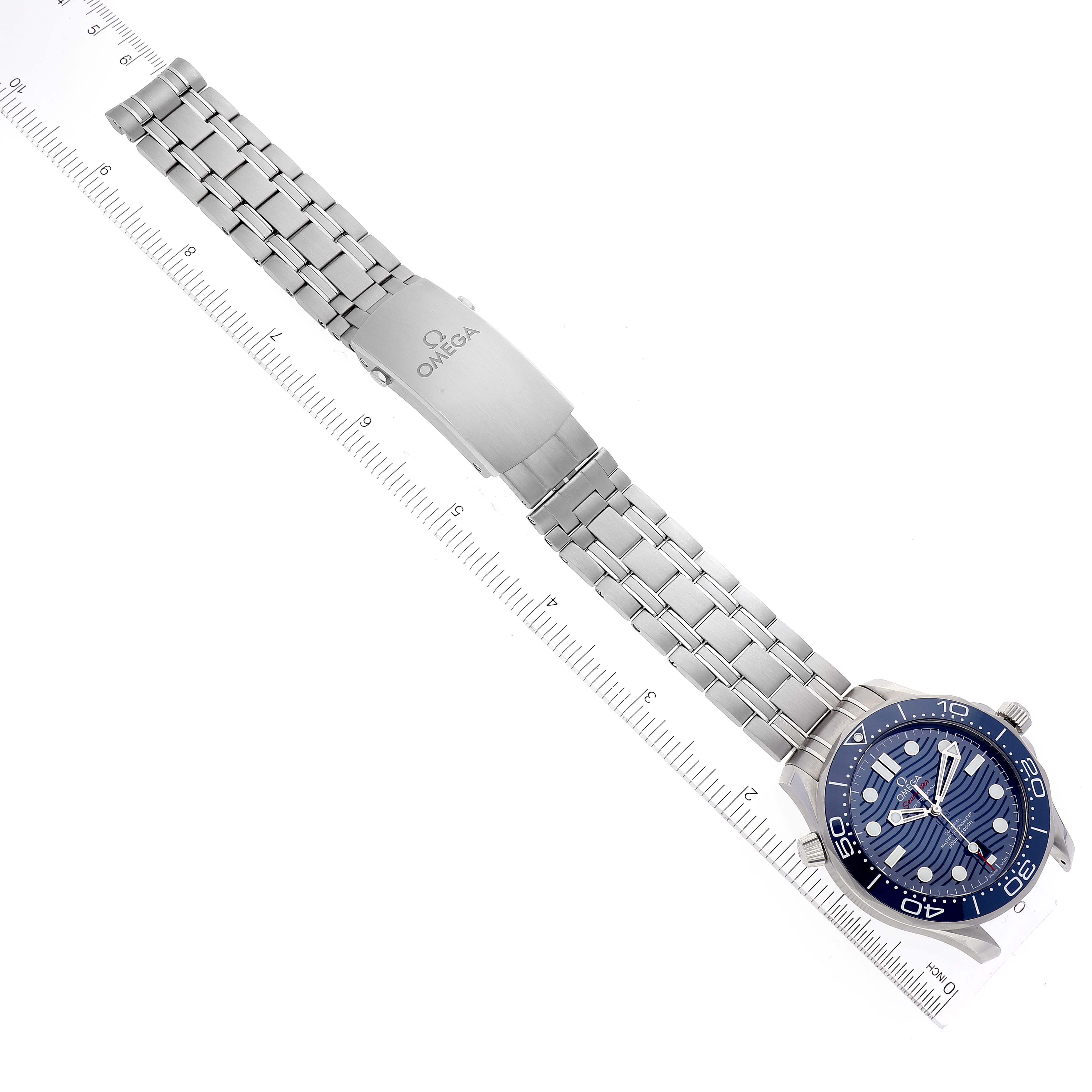 The image shows a top view of an Omega Seamaster 210.30.42.20.03.001 Men's Stainless Steel Blue Dial 210.30.42.20.03.001 Men's Stainless Steel Blue Dial watch, focusing on the face, bracelet, and clasp against a ruler.