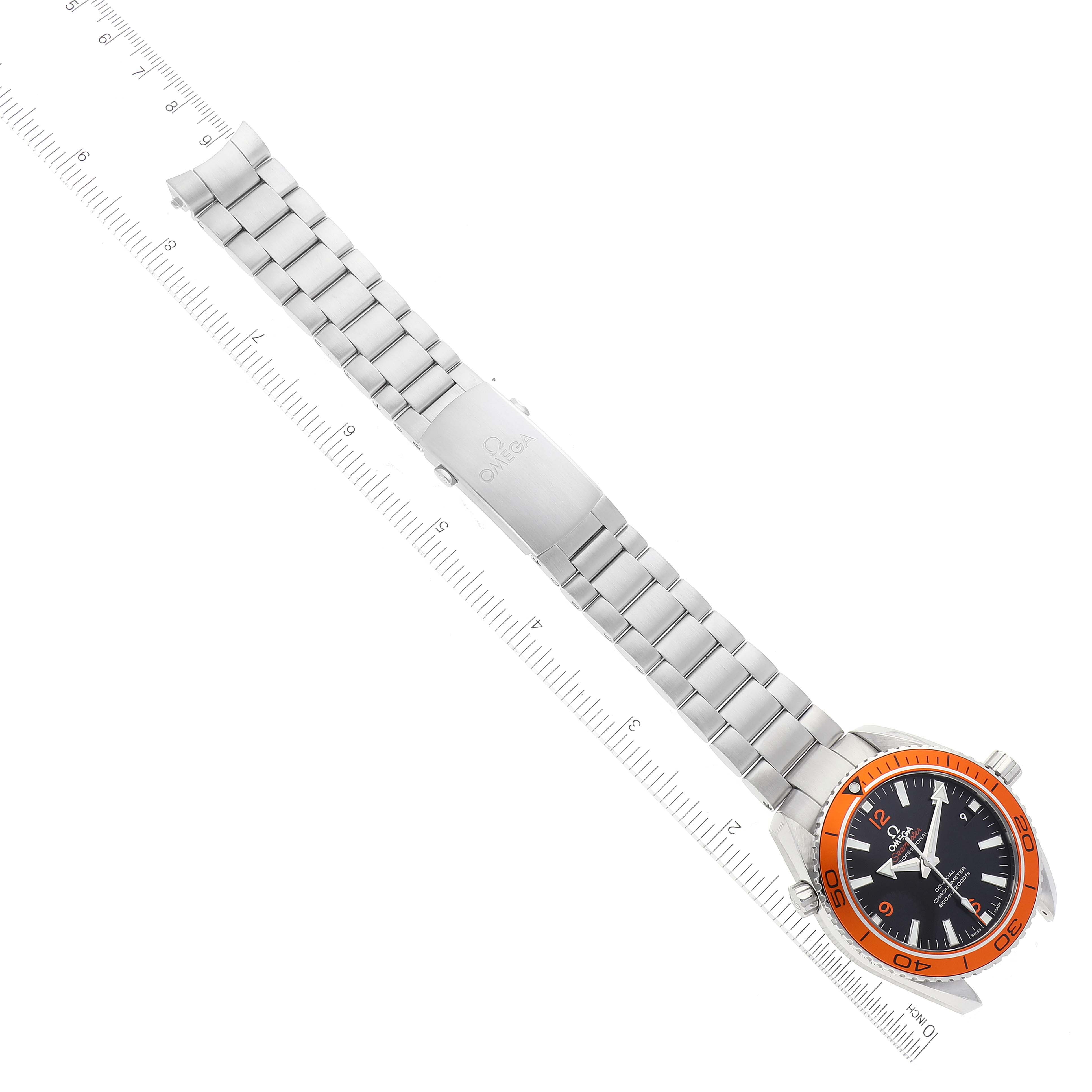 The image shows an overhead view of the Omega Planet Ocean 232.30.42.21.01.002 Men's Stainless Steel Black Dial 232.30.42.21.01.002 Men's Stainless Steel Black Dial watch, including its face, bezel, and metal bracelet next to a ruler.