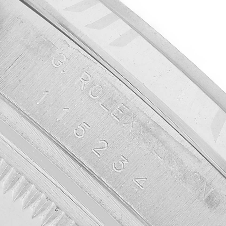The image shows a close-up of the inner engraving on a Rolex Date 115234 Men's Stainless Steel Blue Dial model watch bezel, displaying the brand name and serial number.