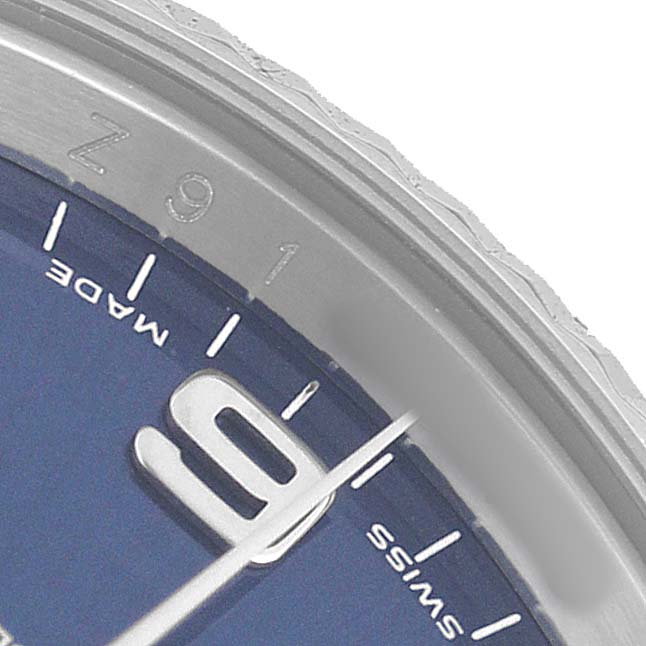 The image shows a close-up of the dial and bezel edge of a Rolex Date 115234 Men's Stainless Steel Blue Dial watch, focusing on the "9" hour marker.