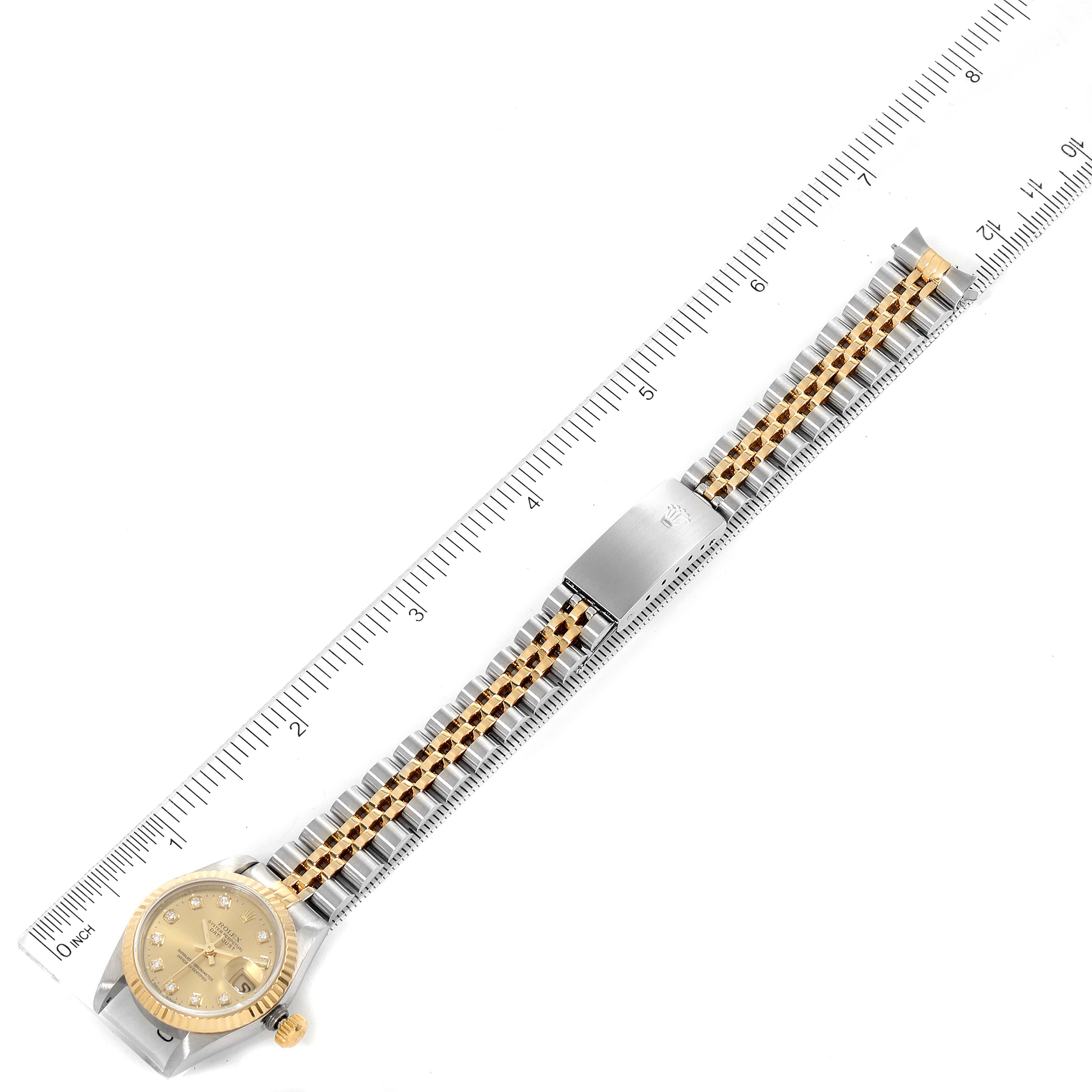 The Rolex Datejust 69173 Women
s Steel and Gold (two tone) Champagne Dial 69173 Women
s Steel and Gold (two tone) Champagne Dial watch is shown from a top-down angle, displaying the full bracelet and dial against a ruler for scale.