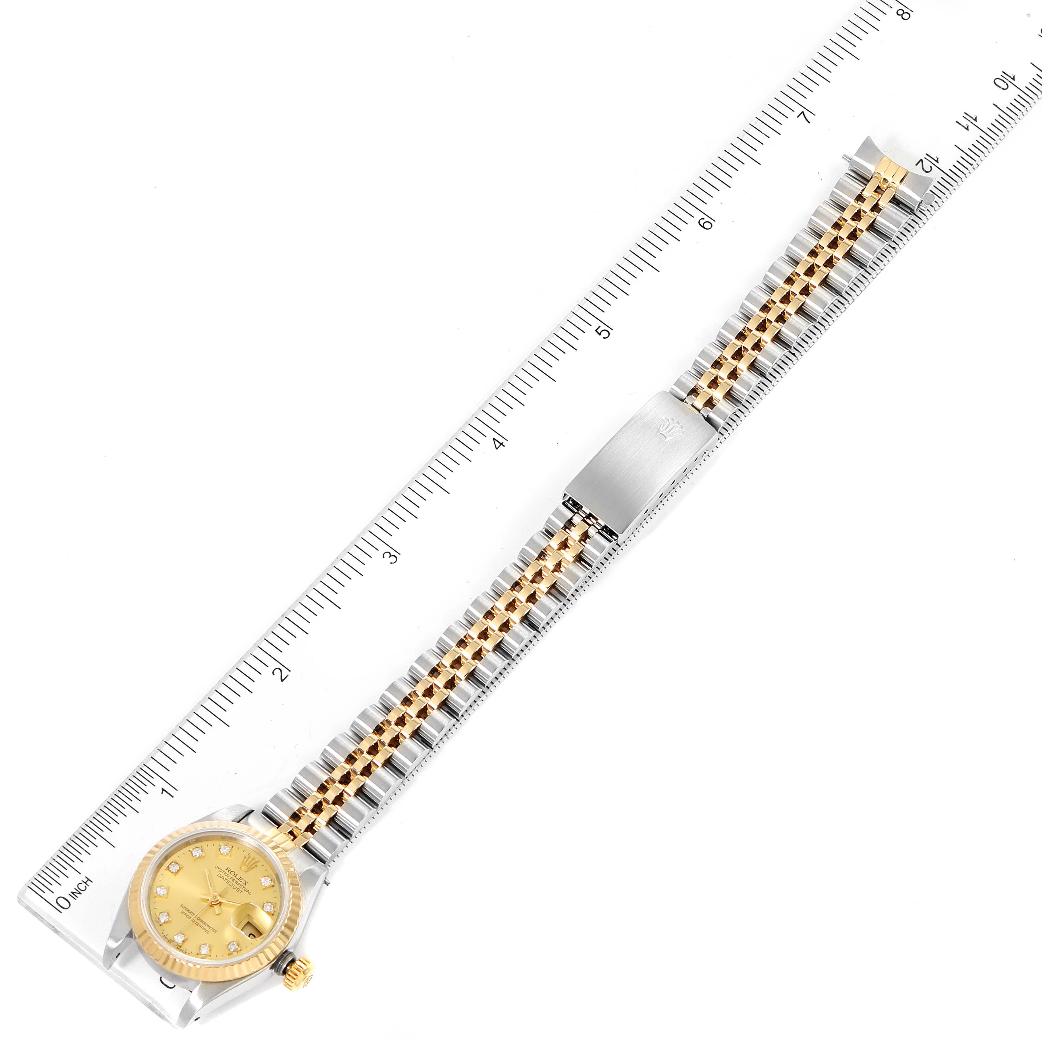 The image shows a Rolex Datejust 69173 Women
s Steel and Gold (two tone) Champagne Dial 69173 Women
s Steel and Gold (two tone) Champagne Dial watch laid flat, with a focus on its bracelet, clasp, and dial, measured by a ruler.