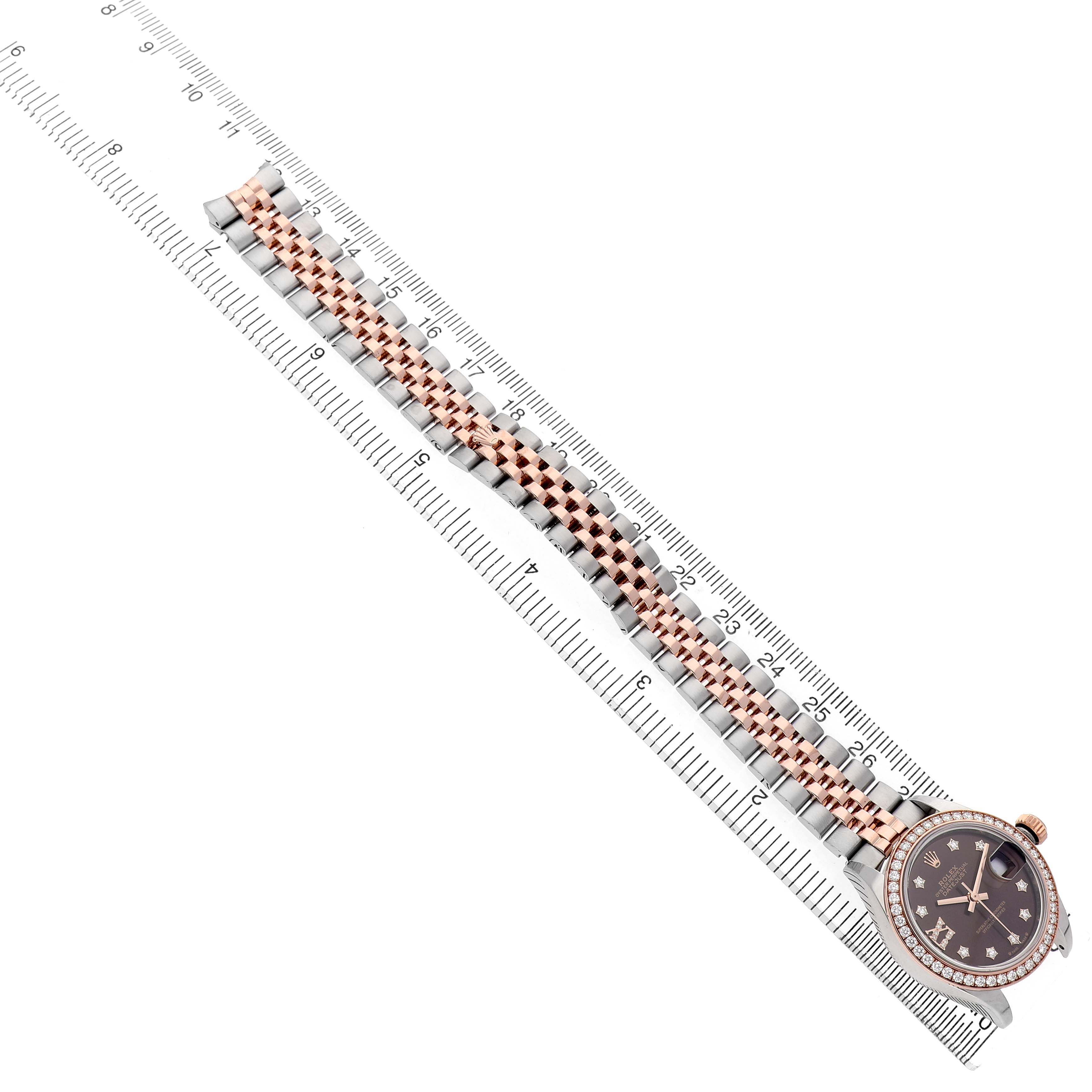 The Rolex Datejust 279381 Women's Stainless Steel Brown Dial watch is shown from a top-down angle, displaying its face and bracelet alongside a ruler for scale.