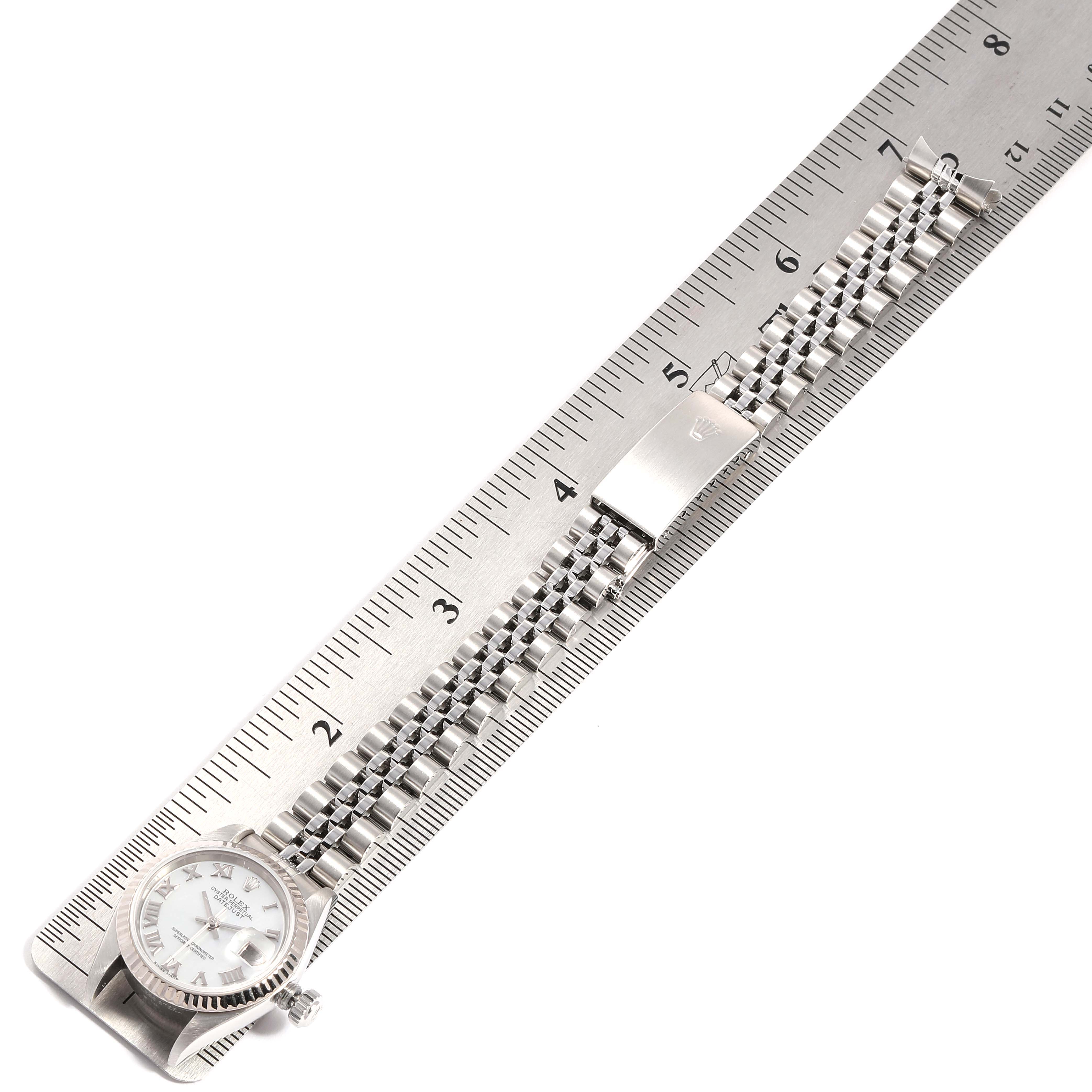 The image shows a Rolex Datejust 79174 Women
s Stainless Steel Mother of Pearl Dial 79174 Women
s Stainless Steel Mother of Pearl Dial watch laid flat next to a ruler, displaying the face, crown, and bracelet with clasp.