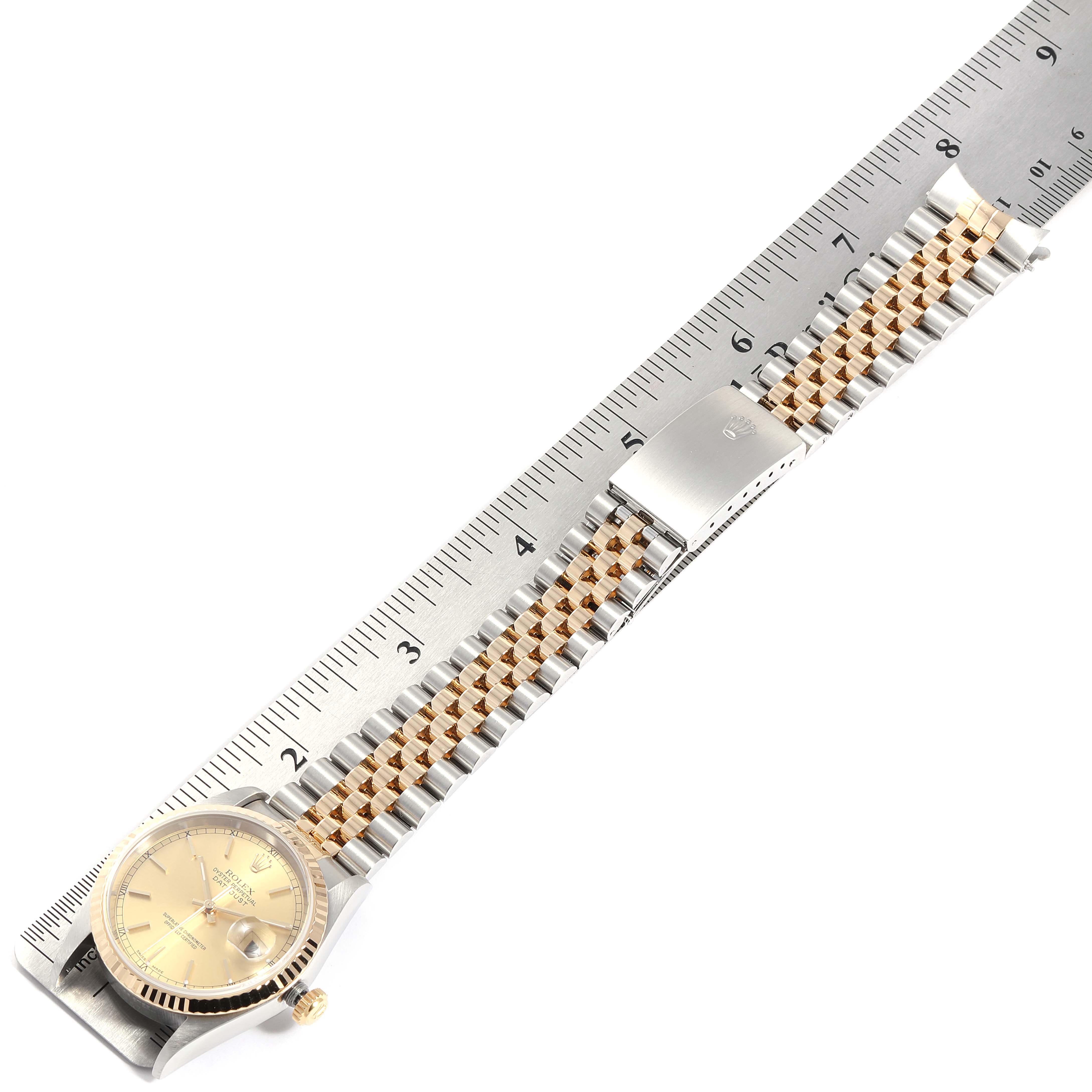 The image shows a Rolex Datejust 16233 Men
s Steel and Gold (two tone) Champagne Dial 16233 Men
s Steel and Gold (two tone) Champagne Dial watch laid flat alongside a ruler, highlighting the face, band, and clasp from an overhead angle.
