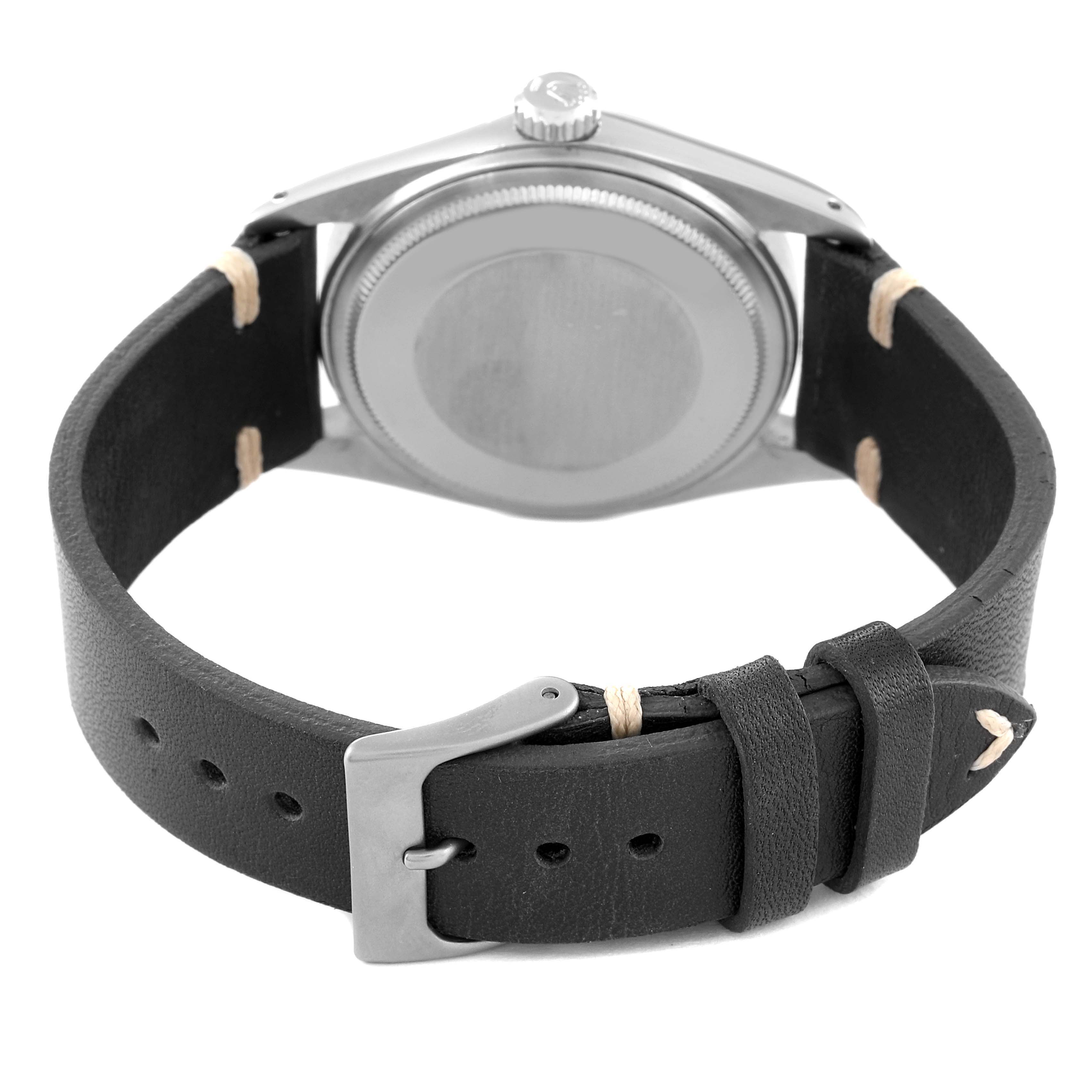 The image shows the back of a Rolex Datejust 1601 Men
s Stainless Steel Black Dial 1601 Men
s Stainless Steel Black Dial watch and its black leather strap with a metal buckle.