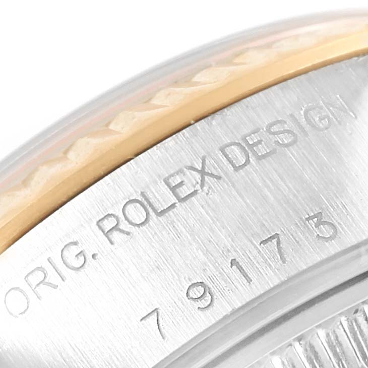 This close-up shows the side of the Rolex Datejust 79173 Women
s Steel and Gold (two tone) Mother of Pearl Dial 79173 Women
s Steel and Gold (two tone) Mother of Pearl Dial watch case, displaying the engraved "ORIG. ROLEX DESIGN" and a partial serial number.