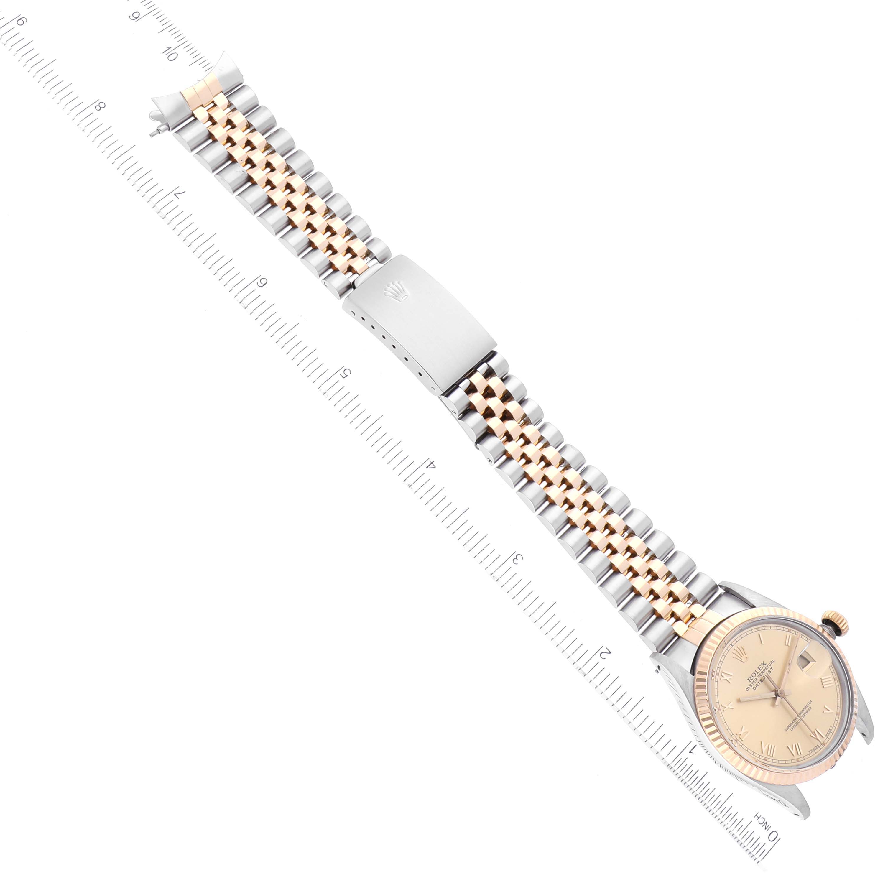 The Rolex Datejust 16013 Men's Steel and Gold (two tone) Champagne Dial 16013 Men's Steel and Gold (two tone) Champagne Dial watch is shown from a top-down angle, highlighting its band, clasp, and face along a ruler for scale.