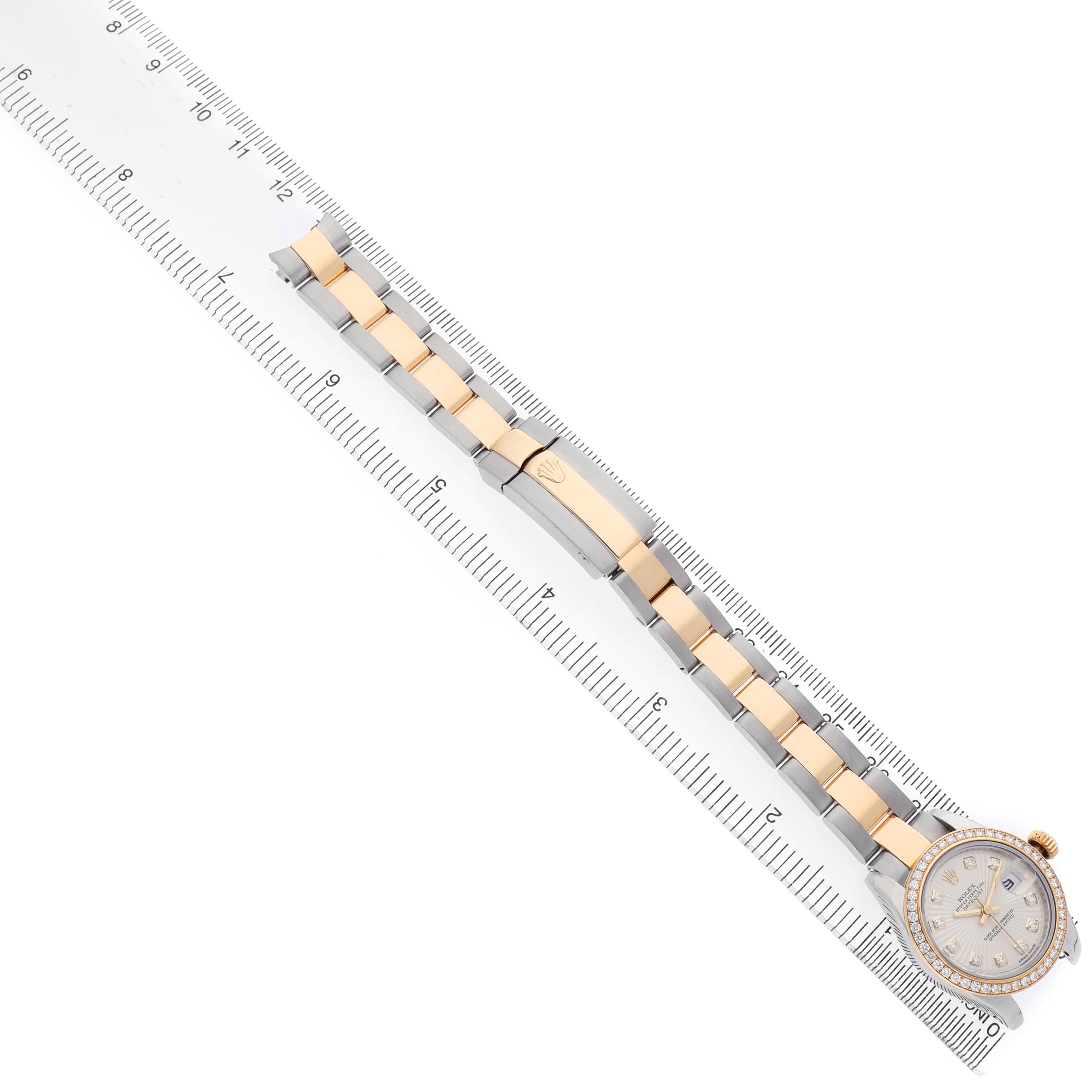 The Rolex Datejust 179383 Women's Steel and Gold (two tone) Silver Dial watch is displayed from a top view, showcasing its bracelet, clasp, and face alongside a ruler for scale.
