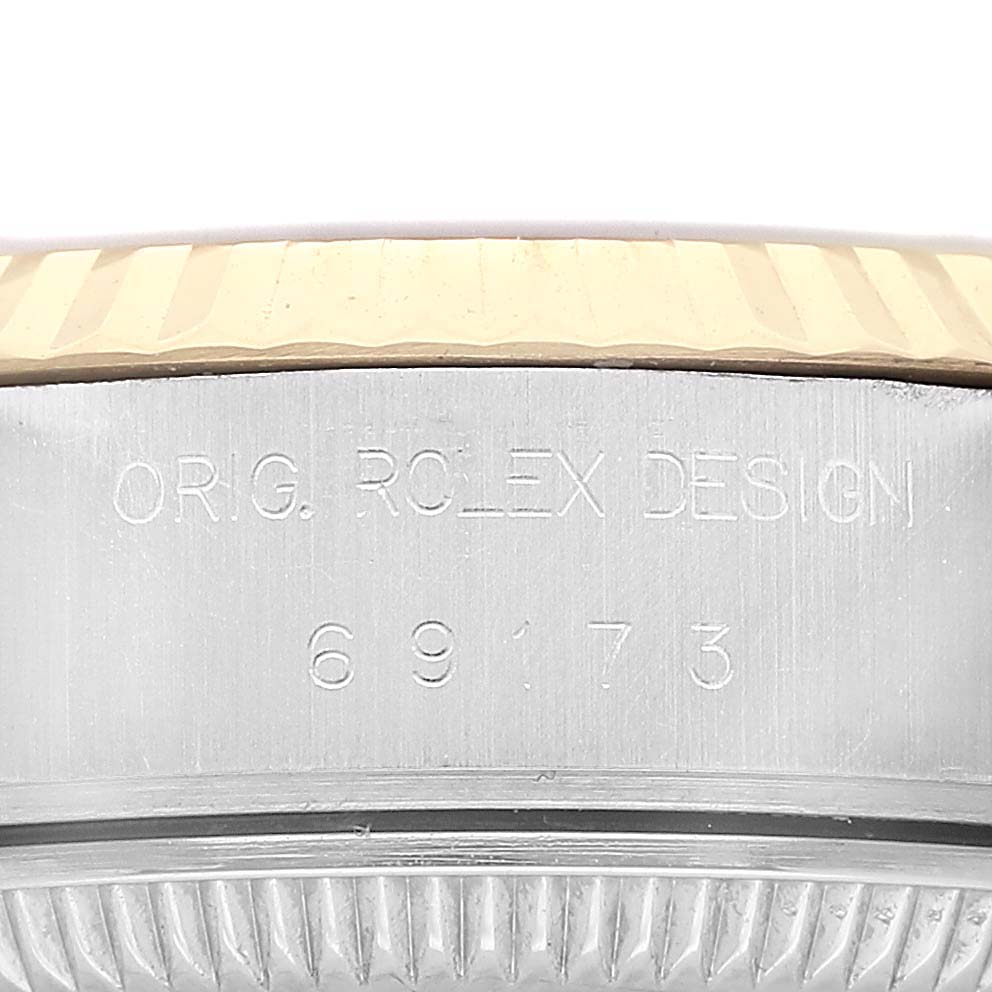 The image shows a side angle of the Rolex Datejust 69173 Women's Steel and Gold (two tone) White Dial model, highlighting the engraved case and fluted bezel.