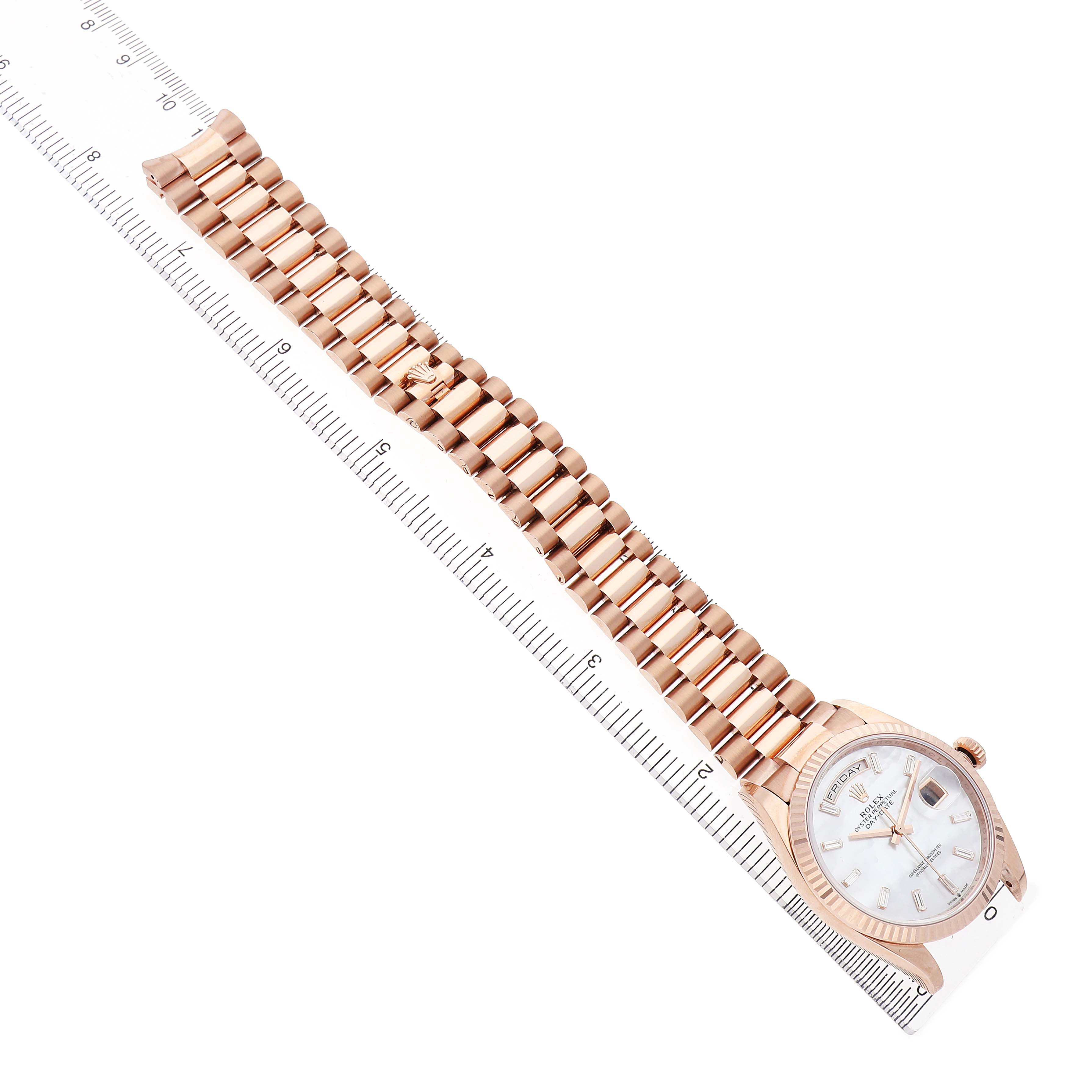 The Rolex President 128235 Men's Rose Gold Mother of Pearl Dial watch is shown from a top-down angle, displaying the bracelet and watch face alongside a ruler for scale.