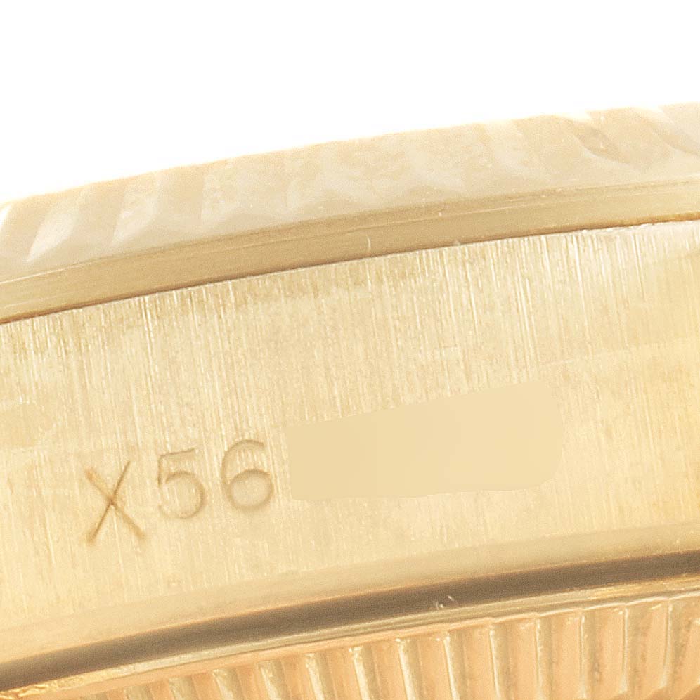 The image shows a close-up of the side of the Rolex President 67198 Women
s Yellow Gold Champagne Dial 67198 Women
s Yellow Gold Champagne Dial model watch, featuring part of the bezel and a serial number engraving.