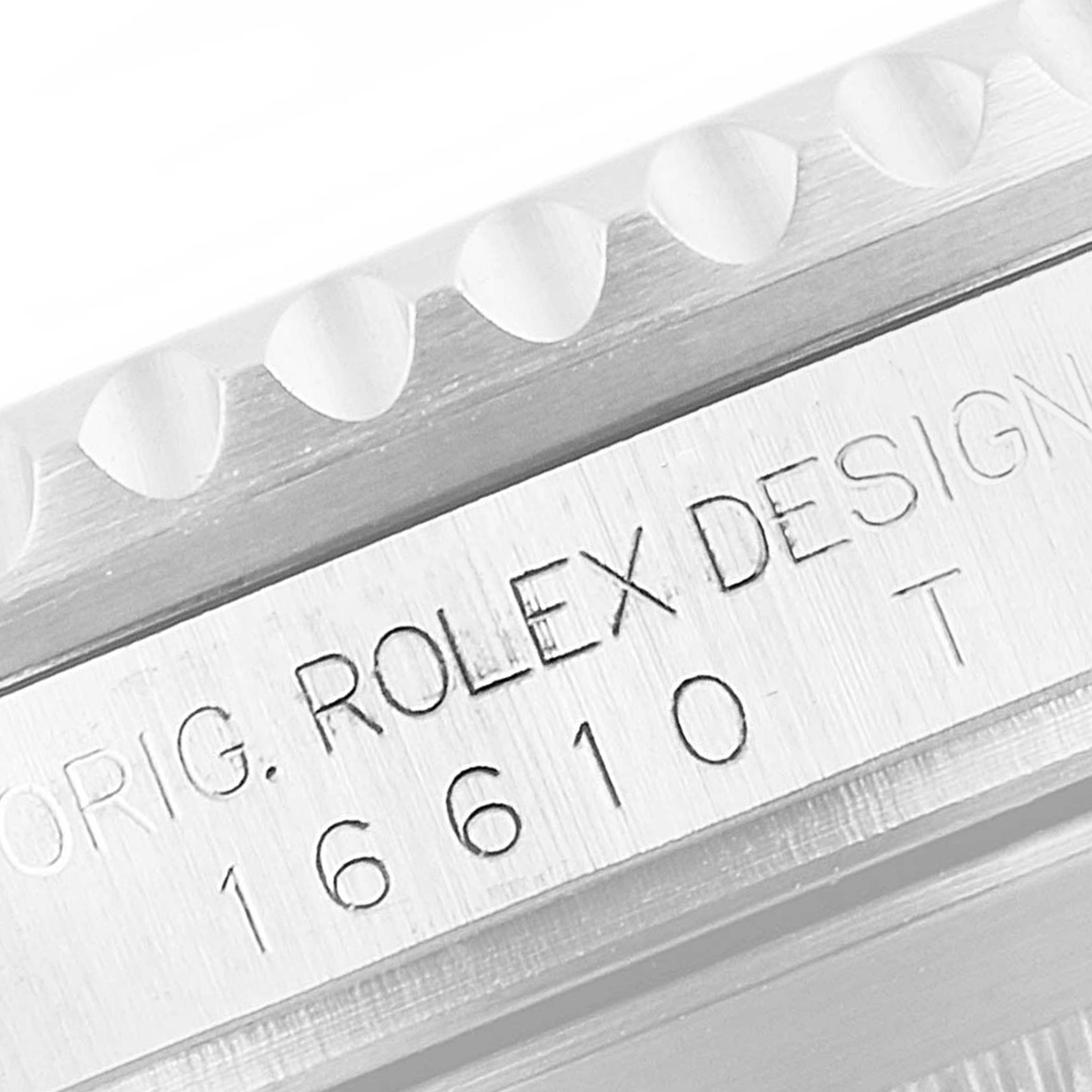 The image shows a close-up of the Rolex Submariner 16610LV Men
s Stainless Steel Black Dial 16610LV Men
s Stainless Steel Black Dial model 16610, focusing on the engraved serial number and bezel edge.