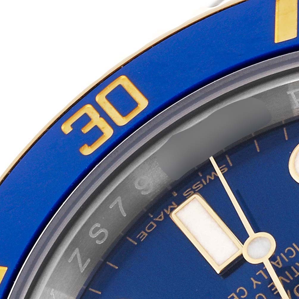 This close-up image shows the bezel, a portion of the dial, and part of the hands of a blue Rolex Submariner 116613 Men's Steel and Gold (two tone) Blue Dial 116613 Men's Steel and Gold (two tone) Blue Dial model.