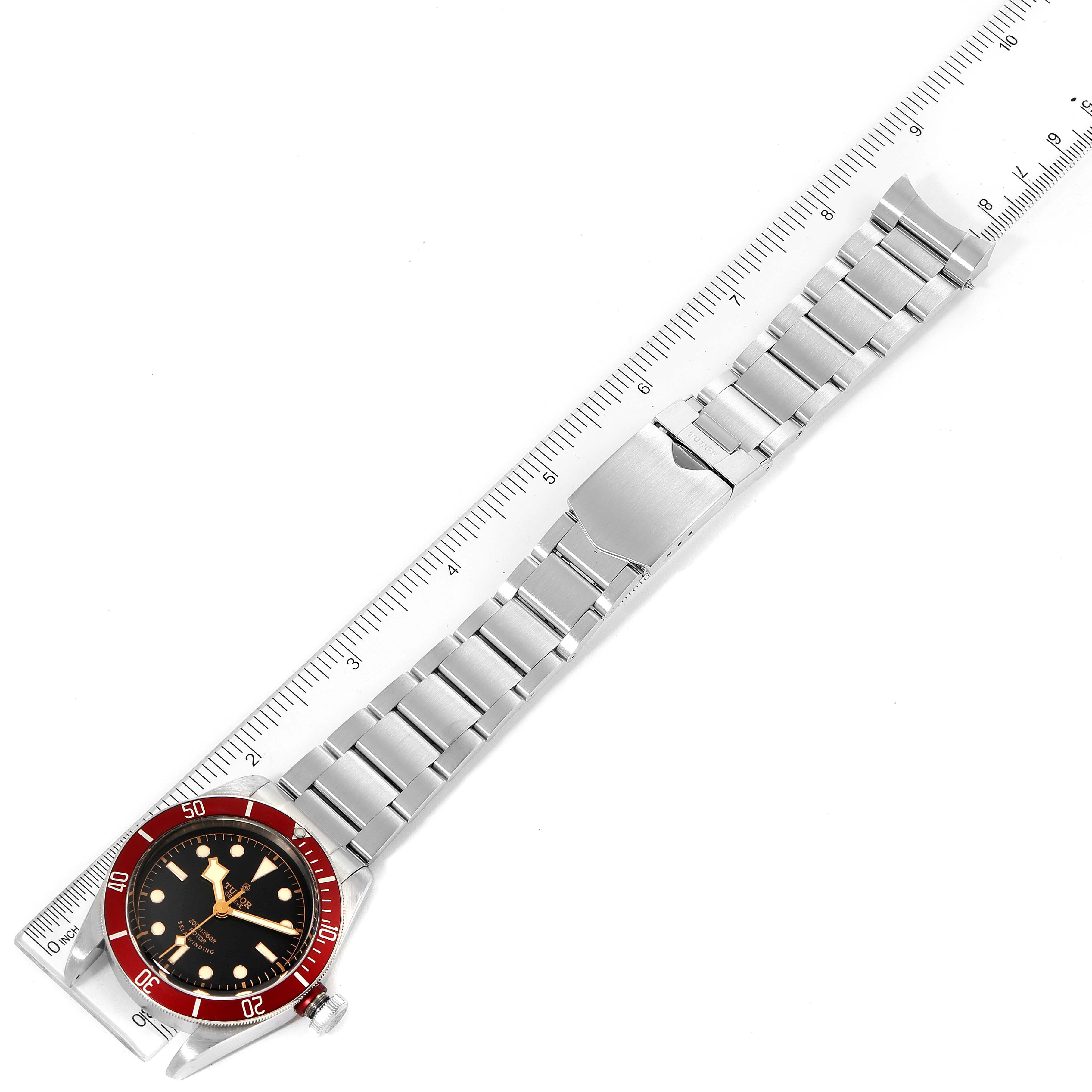 This image shows a Tudor Heritage Black Bay 79220R Men's Stainless Steel Black Dial 79220R Men's Stainless Steel Black Dial watch laid flat with a metal strap measured against a ruler.