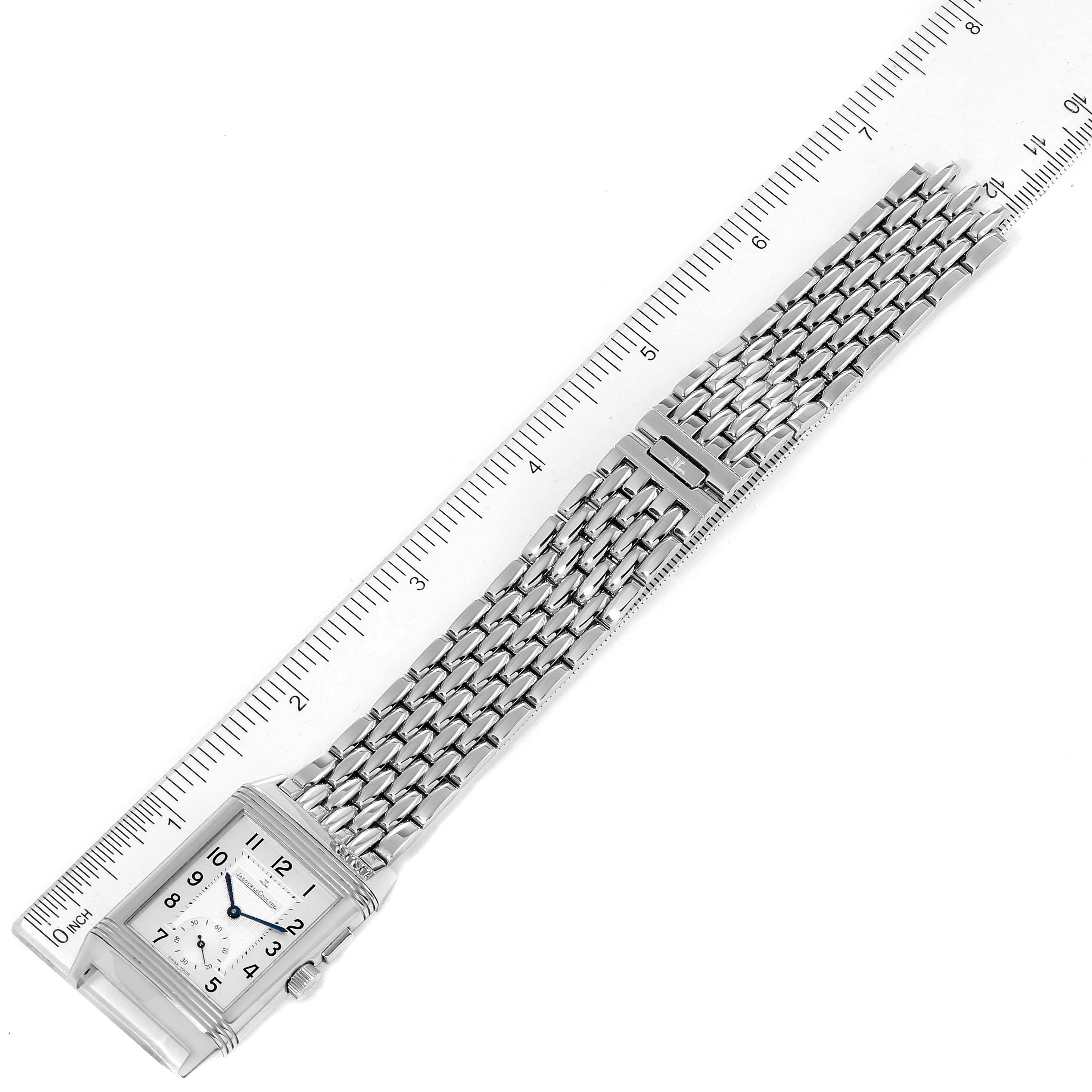 This image shows a Jaeger LeCoultre Reverso Q2458420 Men's Stainless Steel Silver Dial Q2458420 Men's Stainless Steel Silver Dial watch laid flat alongside a ruler, displaying the watch face and metal bracelet.