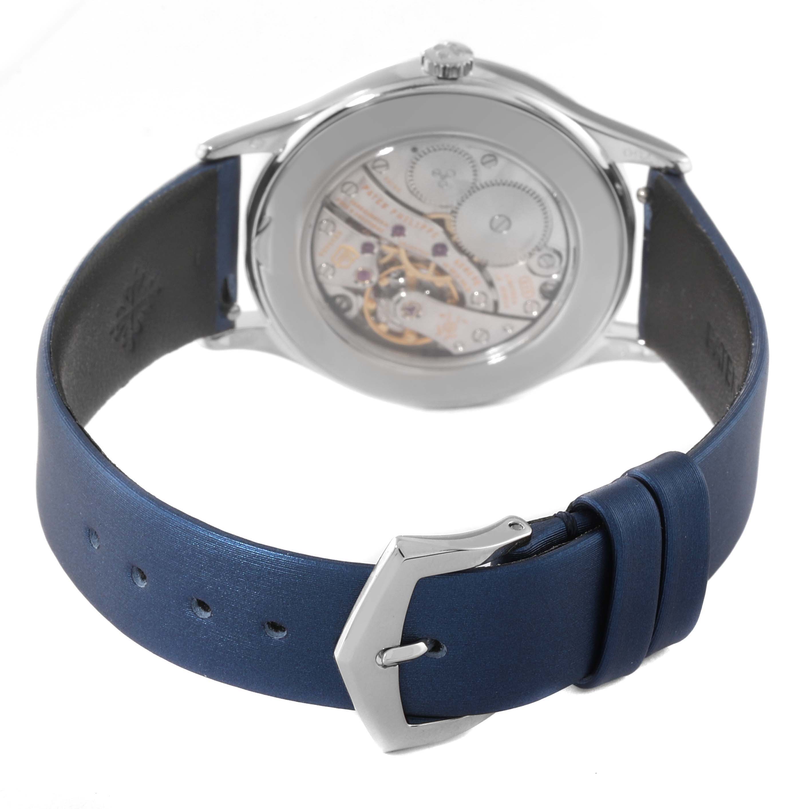 The image displays the backside of a Patek Philippe Calatrava 4897G-001 Women's White Gold Blue Dial 4897G-001 Women's White Gold Blue Dial watch, focusing on its movement and blue leather strap with a silver buckle.