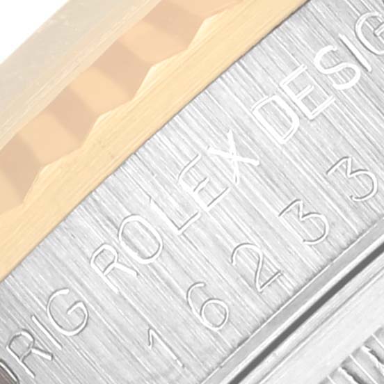 The image shows a close-up of the Rolex Datejust 16233 Men's Steel and Gold (two tone) Black Dial 16233 Men's Steel and Gold (two tone) Black Dial watch's case side engraving and part of the fluted bezel.