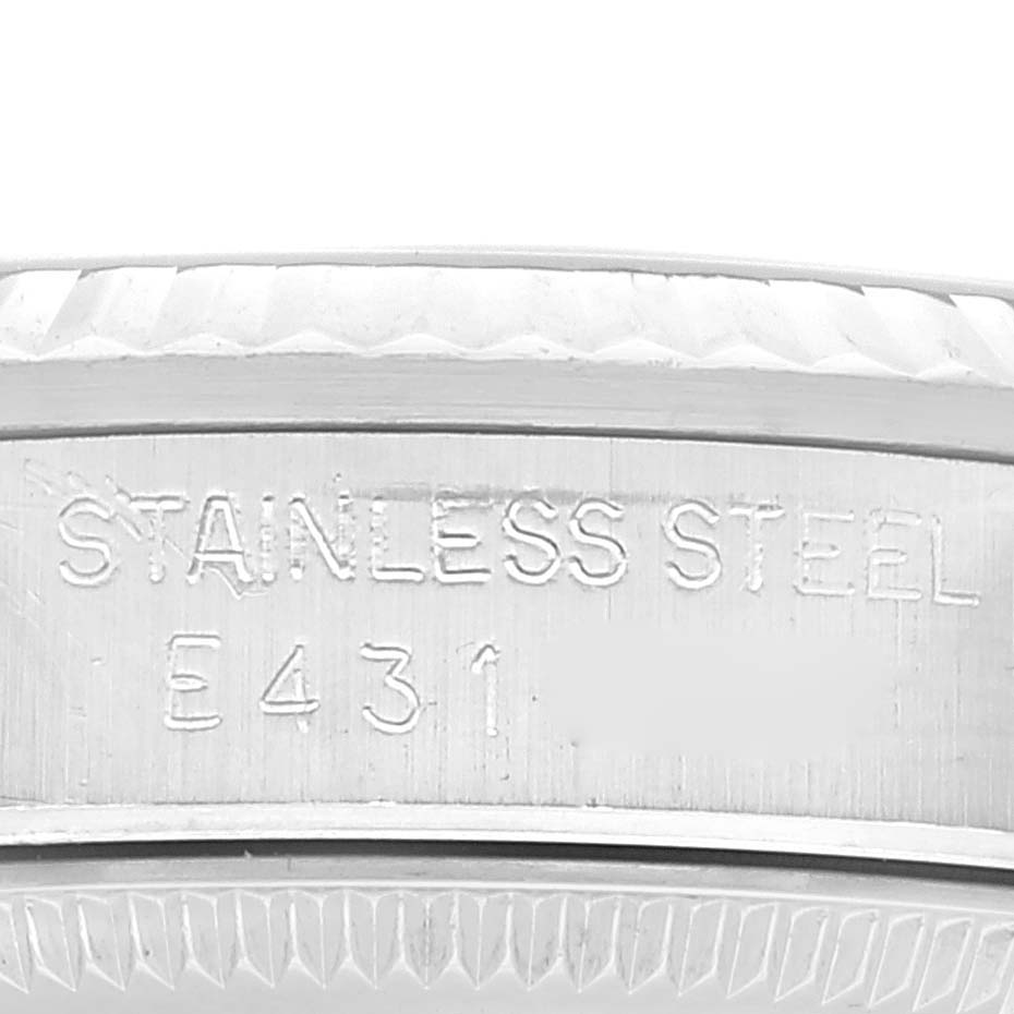 The image shows an extreme close-up of the side of a Mid-Size Rolex watch case, highlighting the stainless steel marking and serial number.