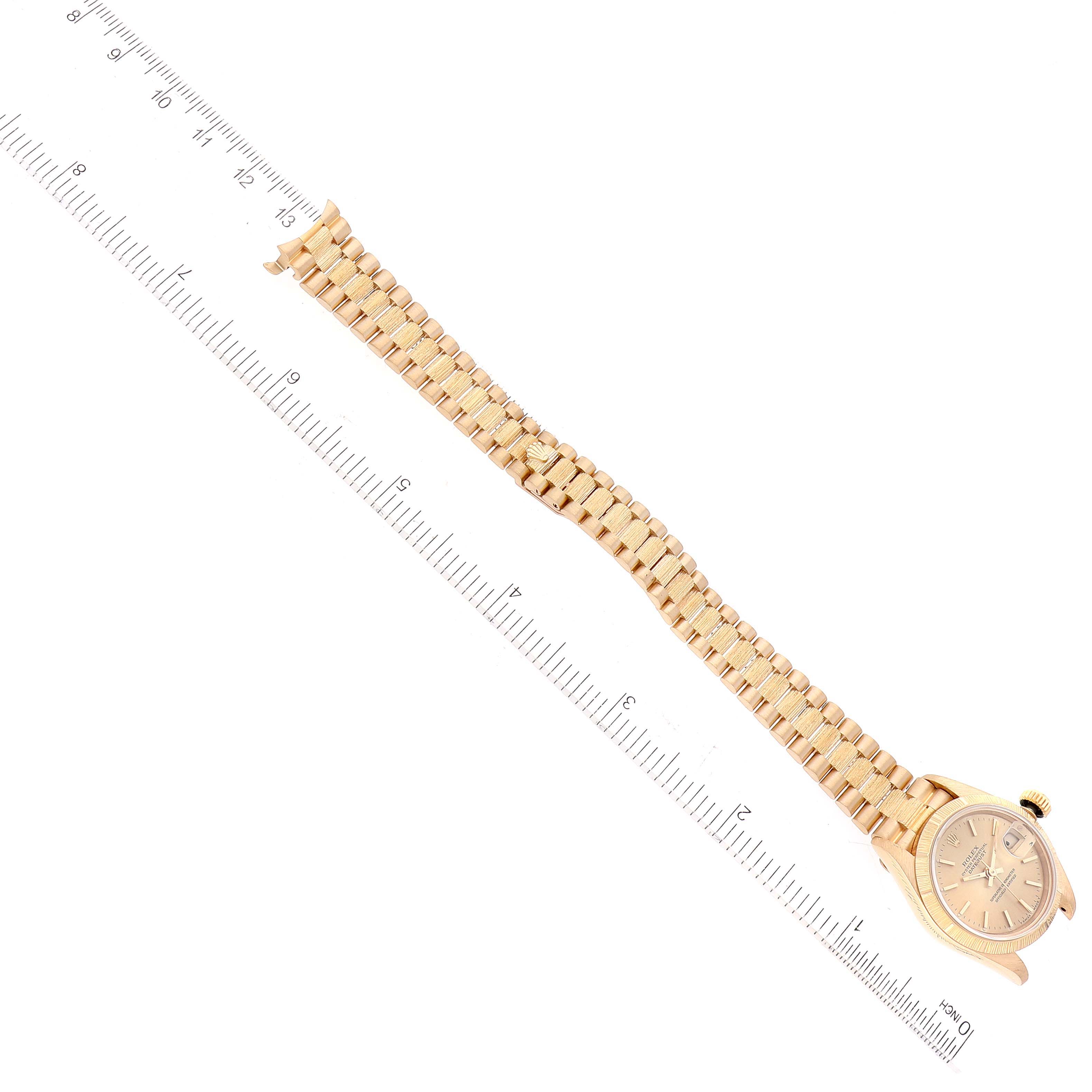 The image shows a Rolex President 69278 Women
s Yellow Gold Champagne Dial 69278 Women
s Yellow Gold Champagne Dial model watch laid flat with its bracelet extended alongside a ruler for measurement.