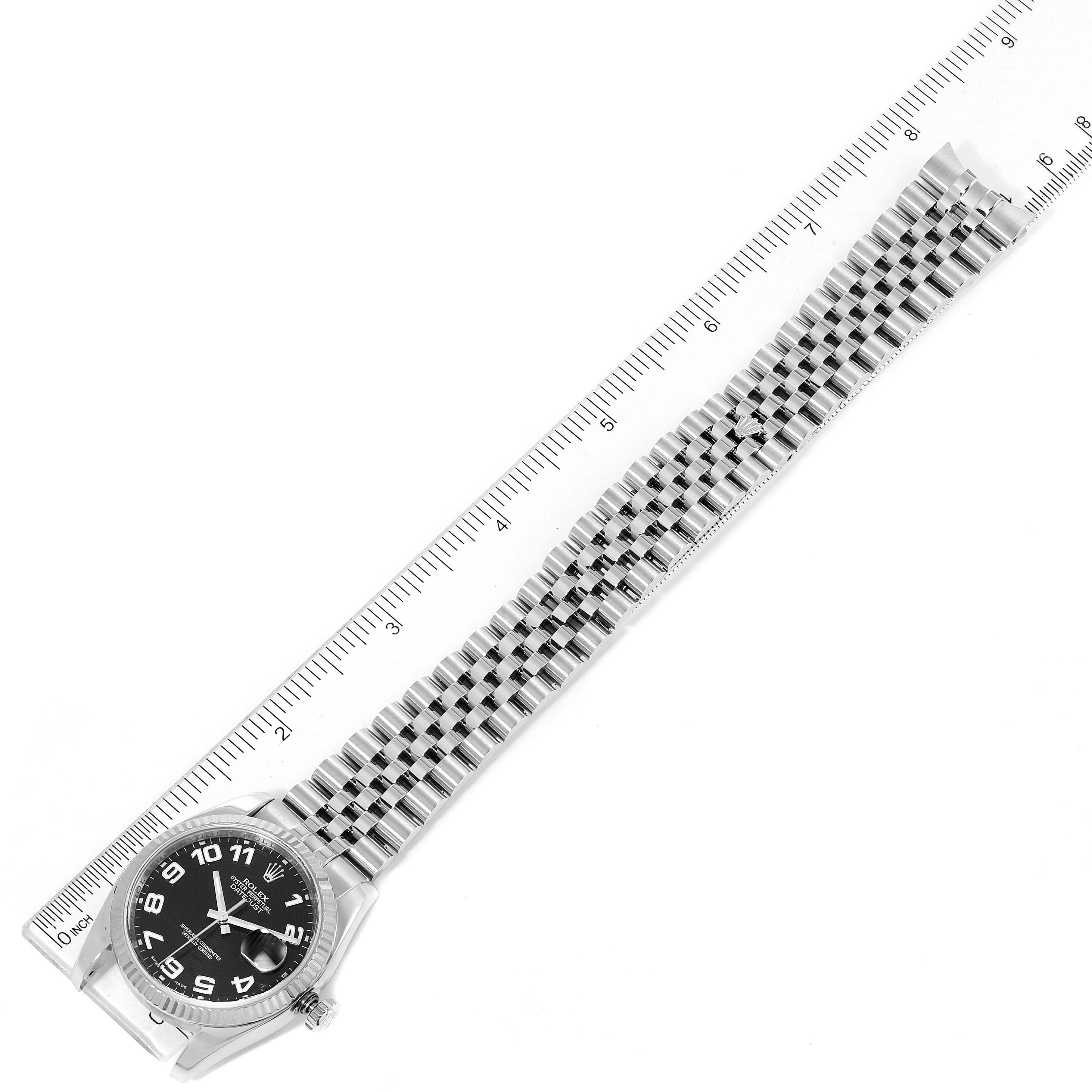 The image shows a top-down view of a Rolex Datejust 116234 Men
s Stainless Steel Black Dial 116234 Men
s Stainless Steel Black Dial watch, including the face, bezel, and full-length metal bracelet placed alongside a ruler.