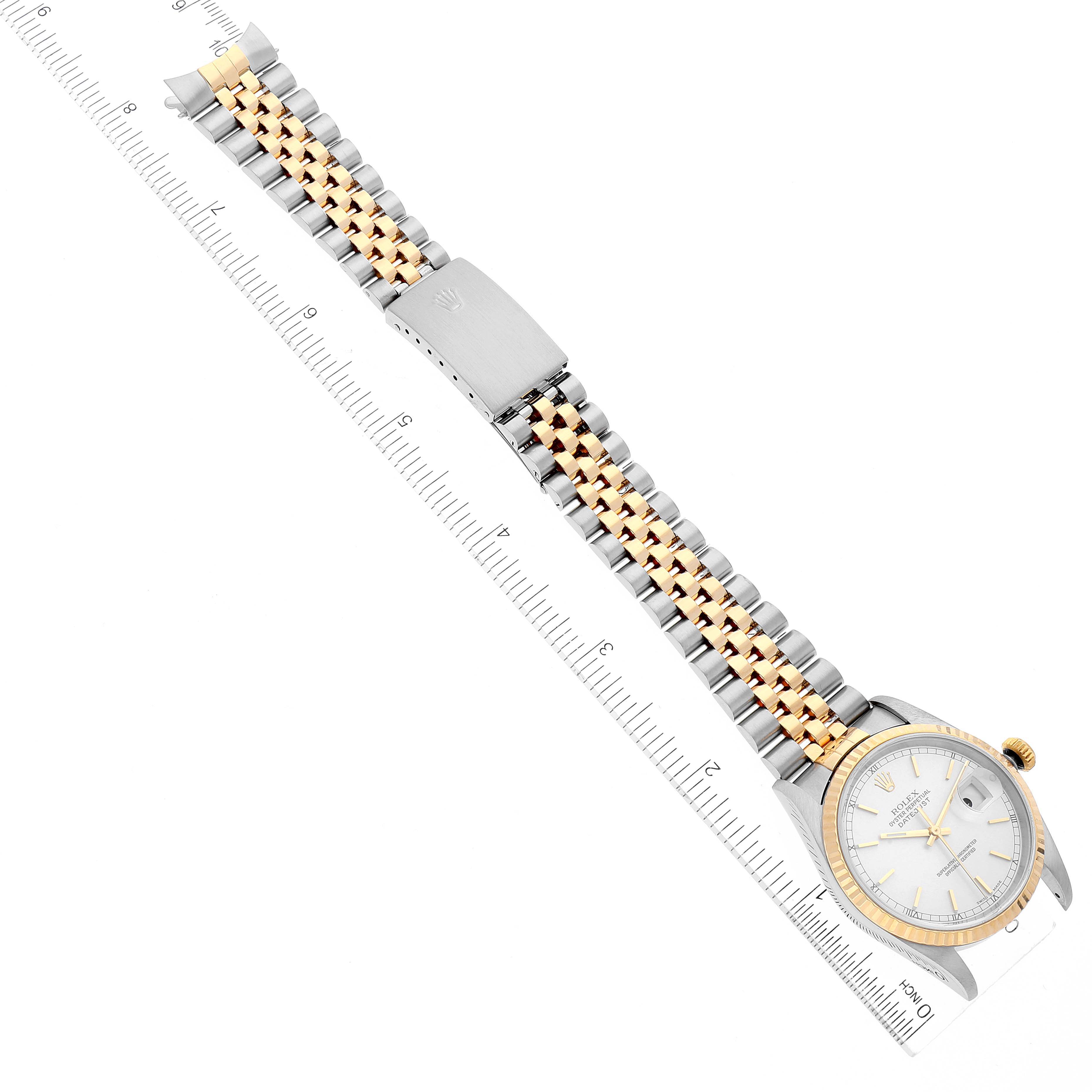 The image shows a top view of a Rolex Datejust 16233 Men's Steel and Gold (two tone) Silver Dial 16233 Men's Steel and Gold (two tone) Silver Dial watch, featuring its bracelet, clasp, and face positioned along a measuring ruler.