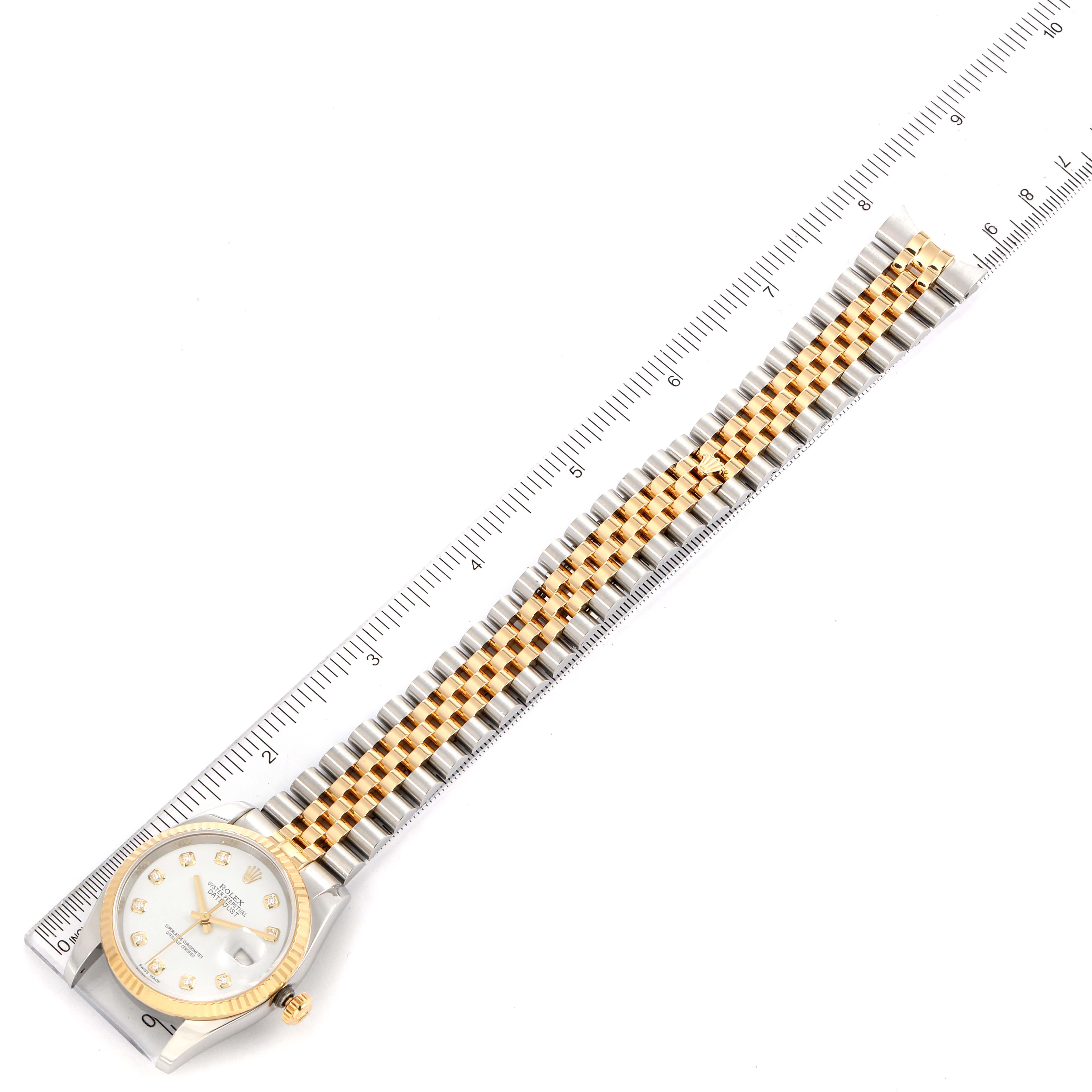 The image shows a Rolex Datejust 116233 Men's Steel and Gold (two tone) White Dial 116233 Men's Steel and Gold (two tone) White Dial watch laid flat next to a ruler, displaying its face and entire band.