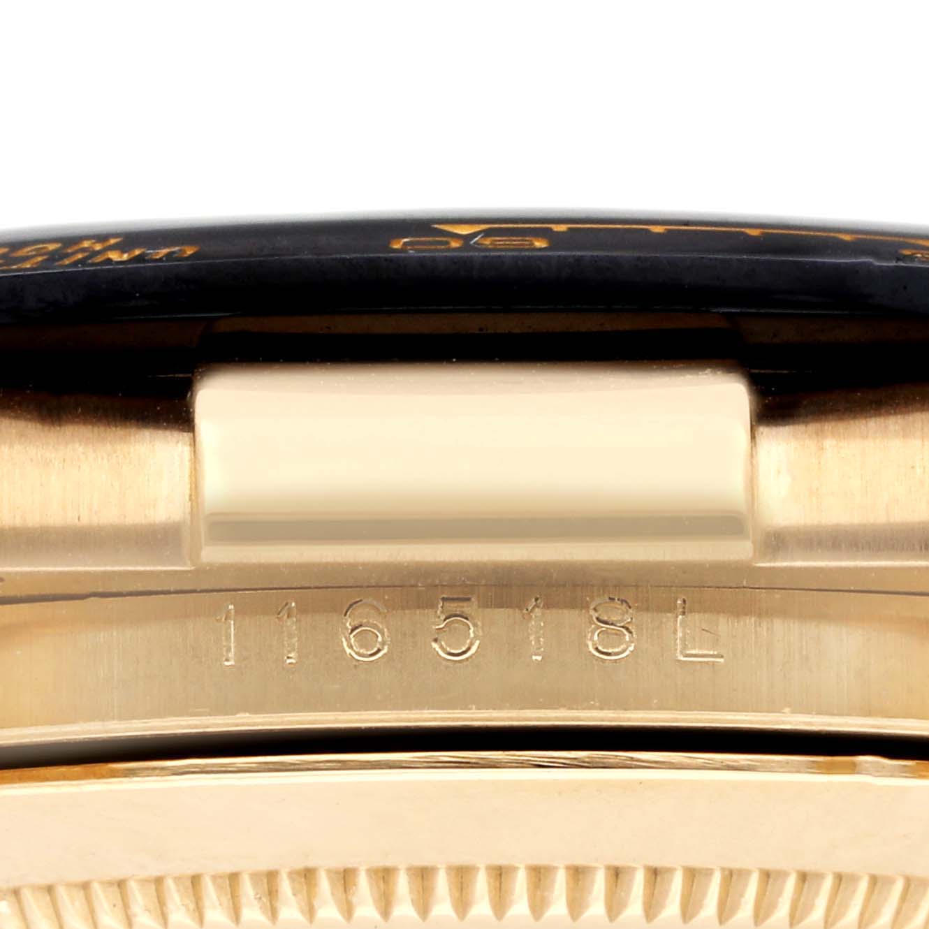 The image shows a close-up of the side of a Rolex Daytona 73019 Men
s Yellow Gold Champagne Dial watch, focusing on the model number engraving and part of the bezel.