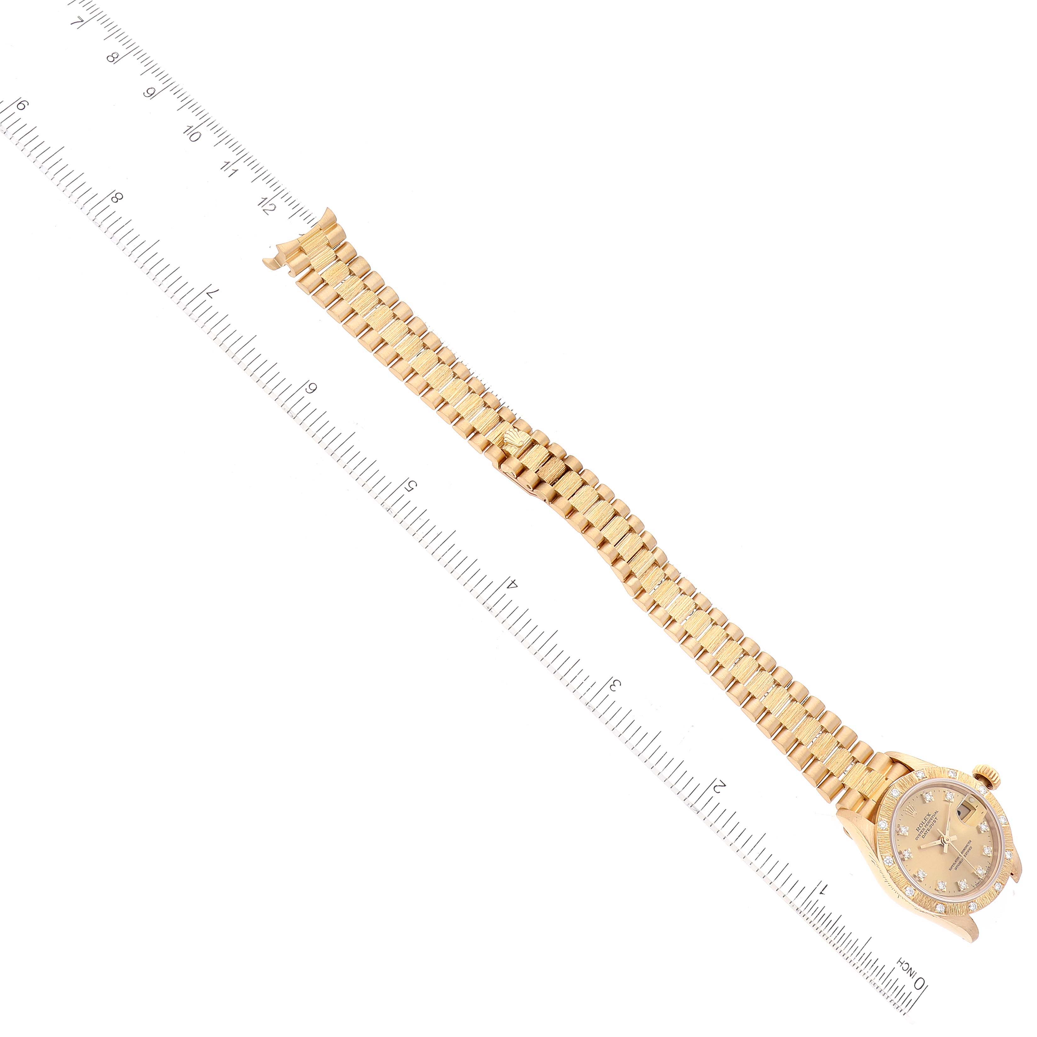 The image shows the Rolex President 69288 Women's Yellow Gold Champagne Dial 69288 Women's Yellow Gold Champagne Dial watch from an overhead angle, highlighting the face, bezel, and bracelet next to a ruler.