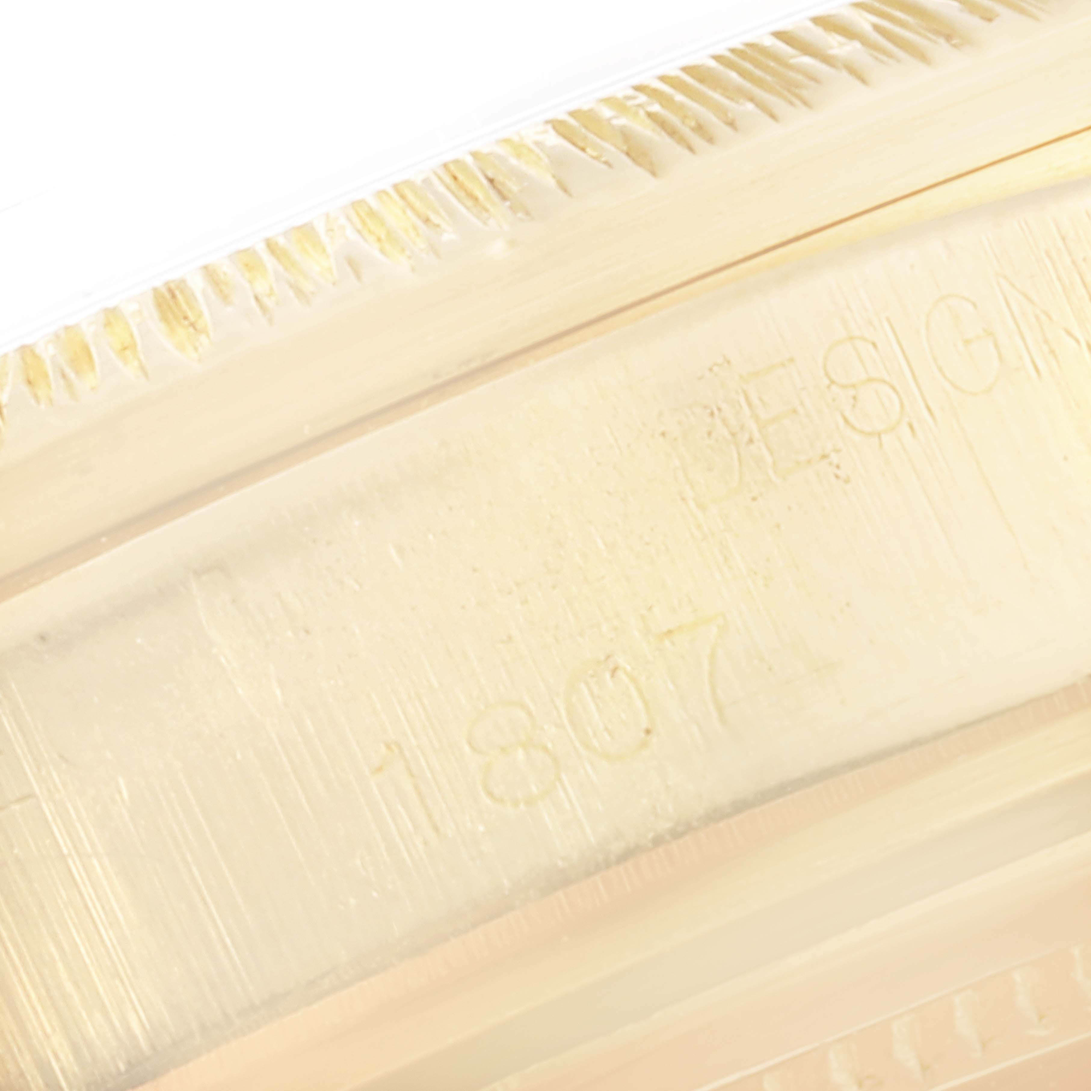 This image shows a close-up of the fluted bezel and engraved model number of a Rolex President 1807 Men's Yellow Gold Black Dial 1807 Men's Yellow Gold Black Dial watch.