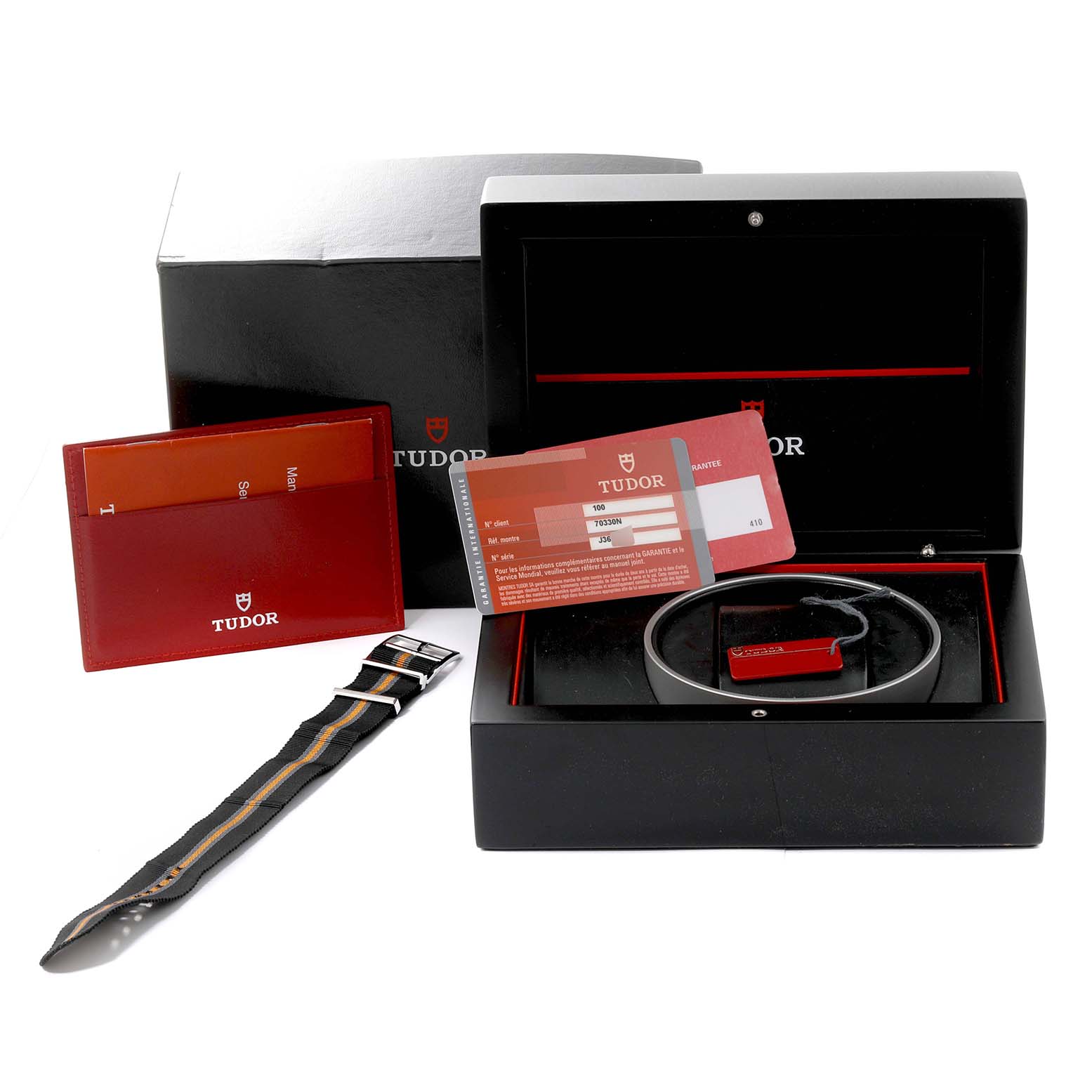 The image shows the Tudor Heritage Chrono 70330N-95740 Men
s Stainless Steel Black Dial 70330N-95740 Men
s Stainless Steel Black Dial watch accessories including the box, warranty card, strap, and documentation.