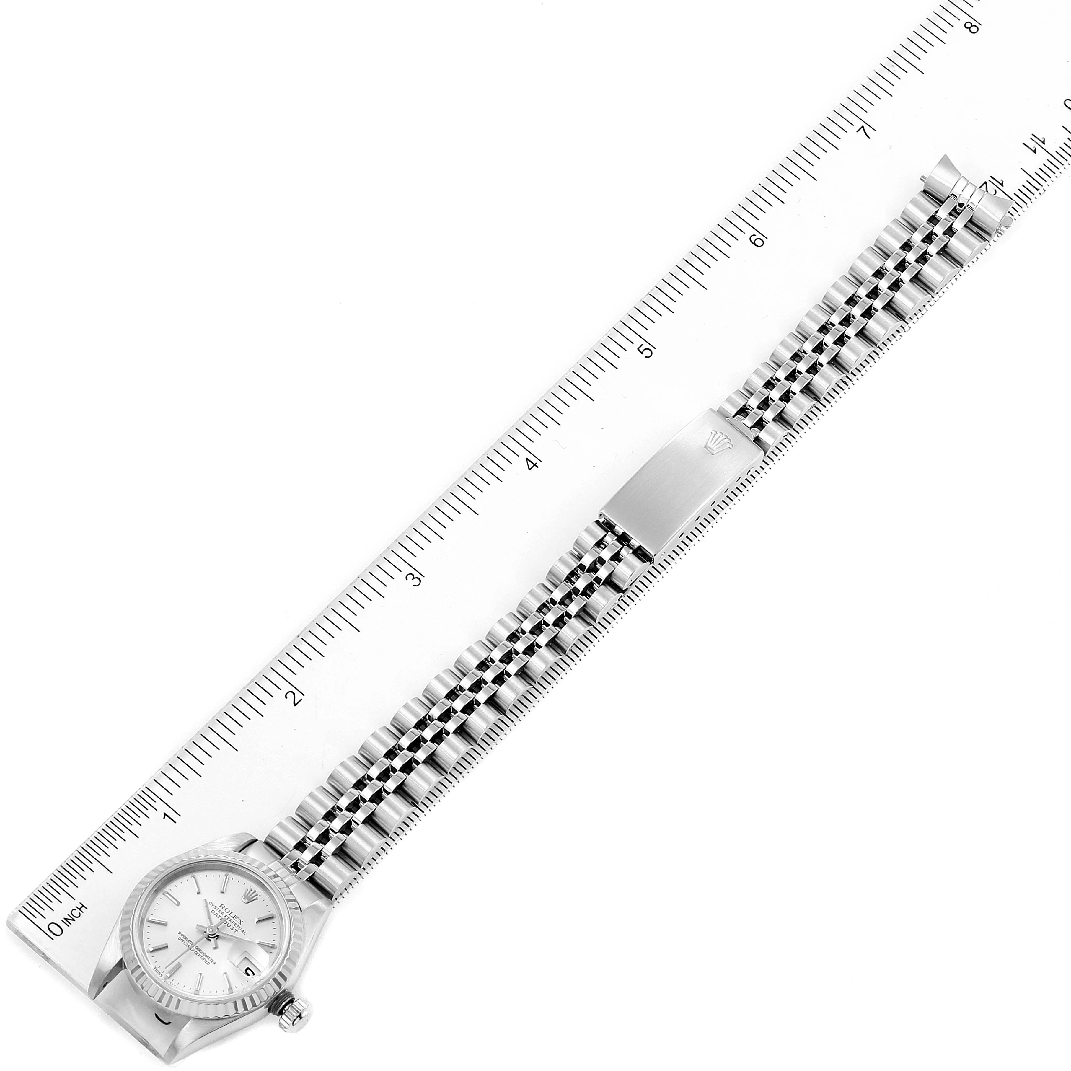 The Rolex Datejust 79174 Women's Stainless Steel Silver Dial 79174 Women's Stainless Steel Silver Dial watch is shown from a top-down angle alongside a ruler, displaying the face, bezel, crown, and bracelet.