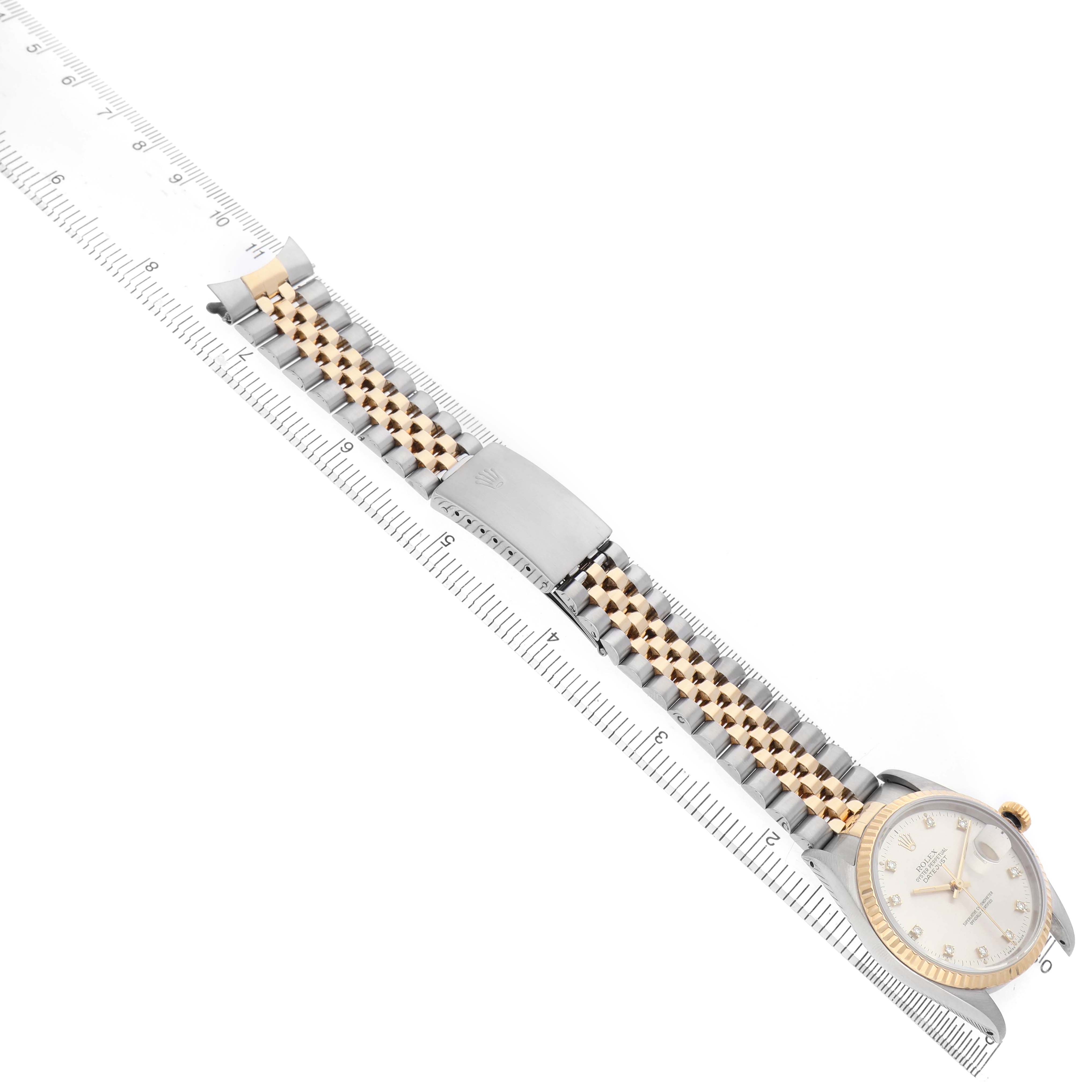 The image shows a Rolex Datejust 16233 Men's Steel and Gold (two tone) Silver Dial watch at an angle, highlighting the bracelet and clasp, laid alongside a ruler for size reference.