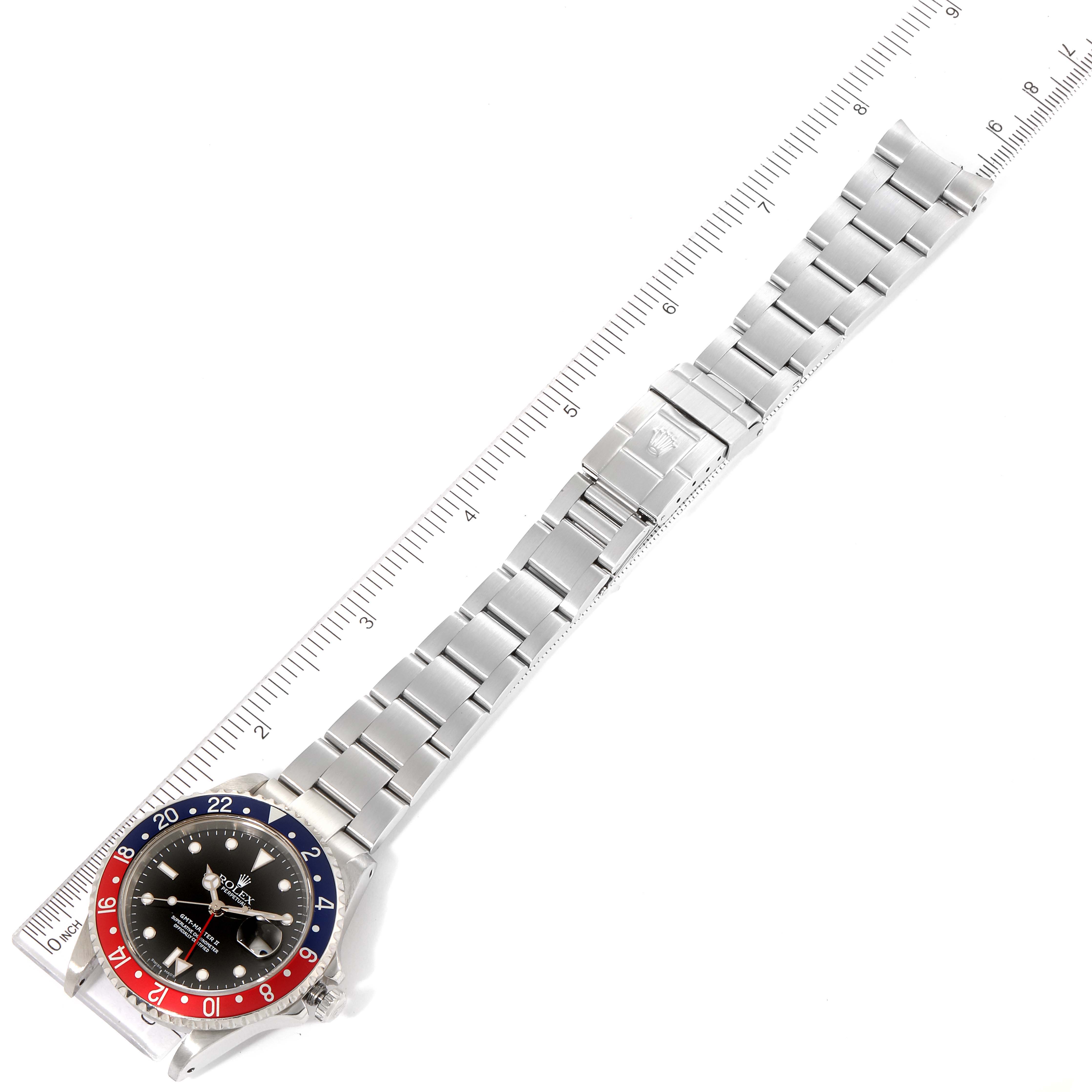 The image shows a full view of a Rolex GMT-Master 16710 Men
s Stainless Steel Black Dial 16710 Men
s Stainless Steel Black Dial watch, including its face, bezel, and metal bracelet, displayed next to a ruler.