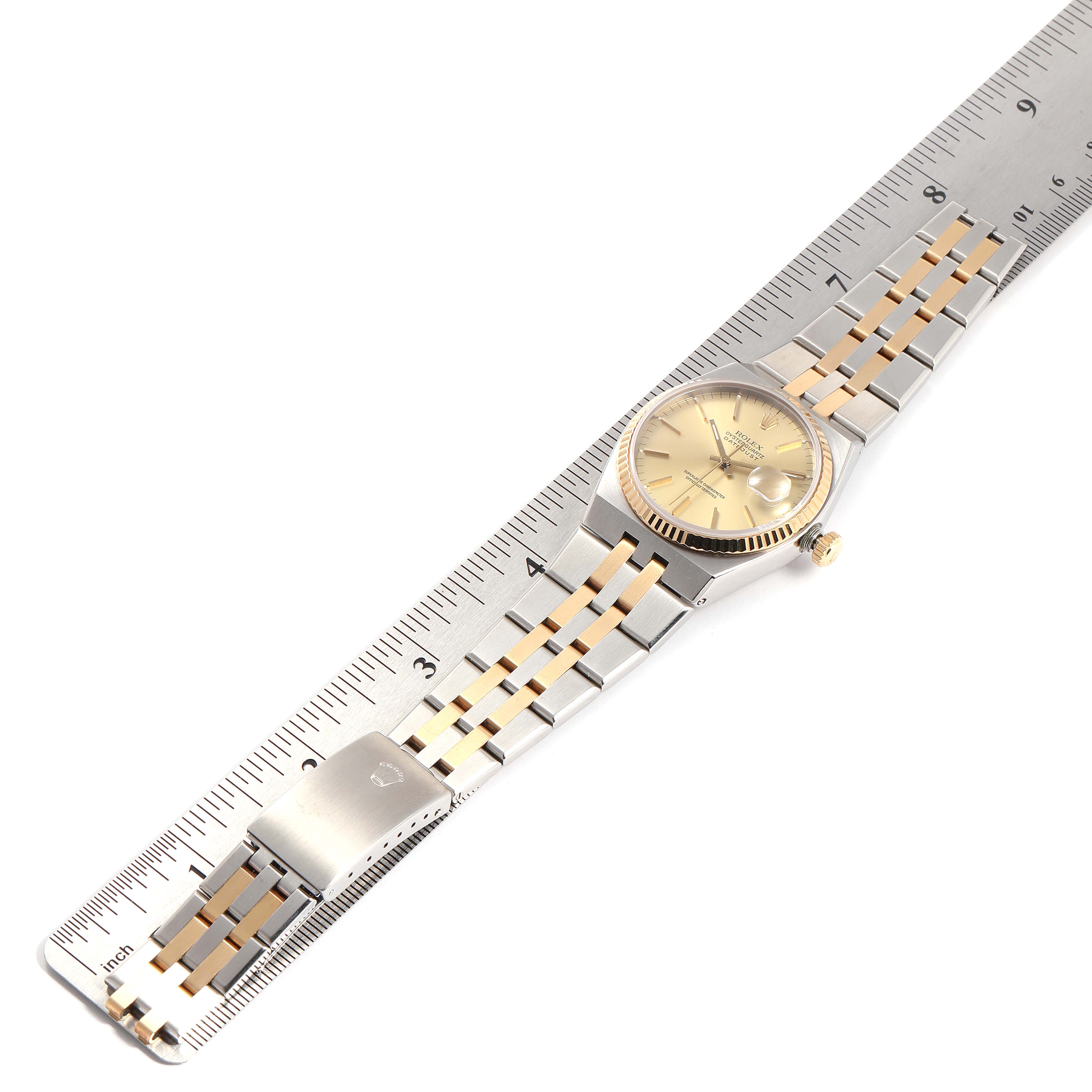 The image shows a Rolex Oysterquartz 19508 Men
s Steel and Gold (two tone) Champagne Dial 19508 Men
s Steel and Gold (two tone) Champagne Dial watch with a stainless steel and gold bracelet laid flat next to a ruler.
