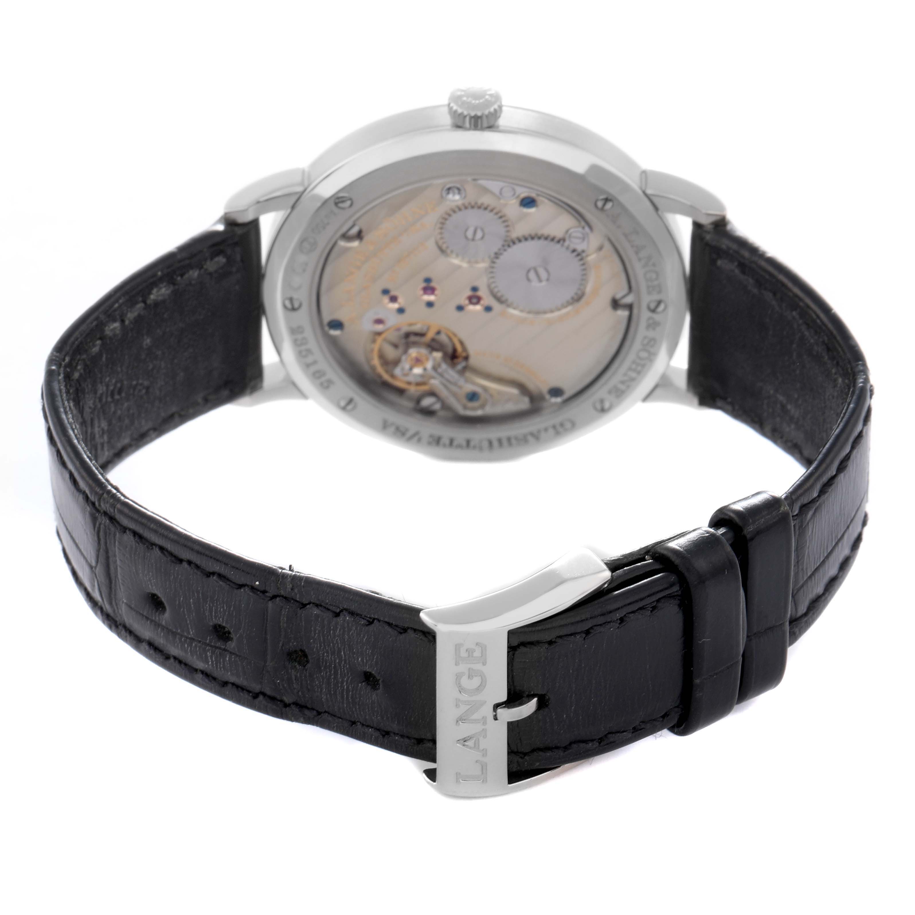 The image shows the back view of the A. Lange & Söhne Saxonia model 201.027, highlighting the movement details and the black leather strap with "LANGE" on the buckle.