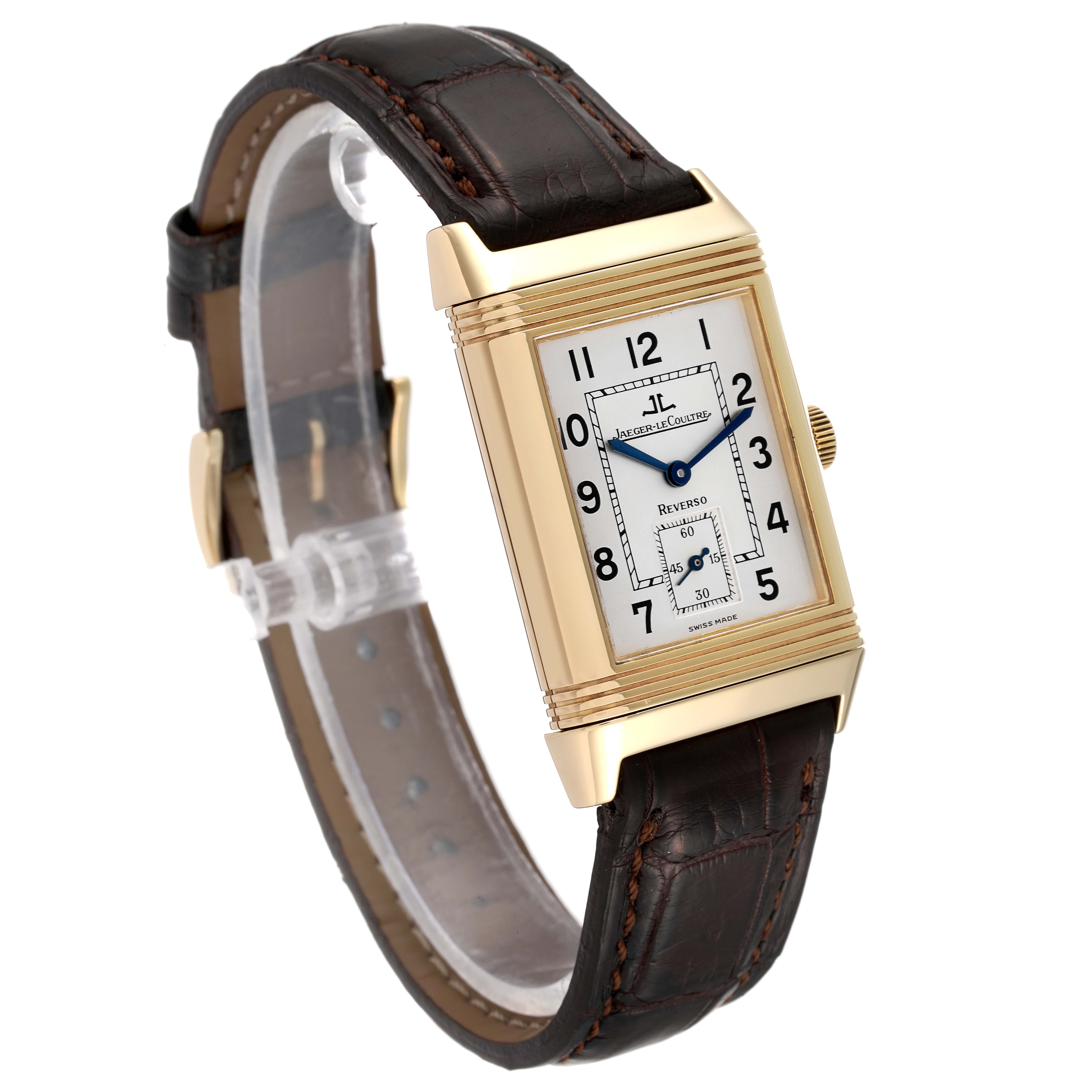 The image shows a Jaeger-LeCoultre Reverso watch at an angled view, highlighting its rectangular face, gold case, and brown leather strap.
