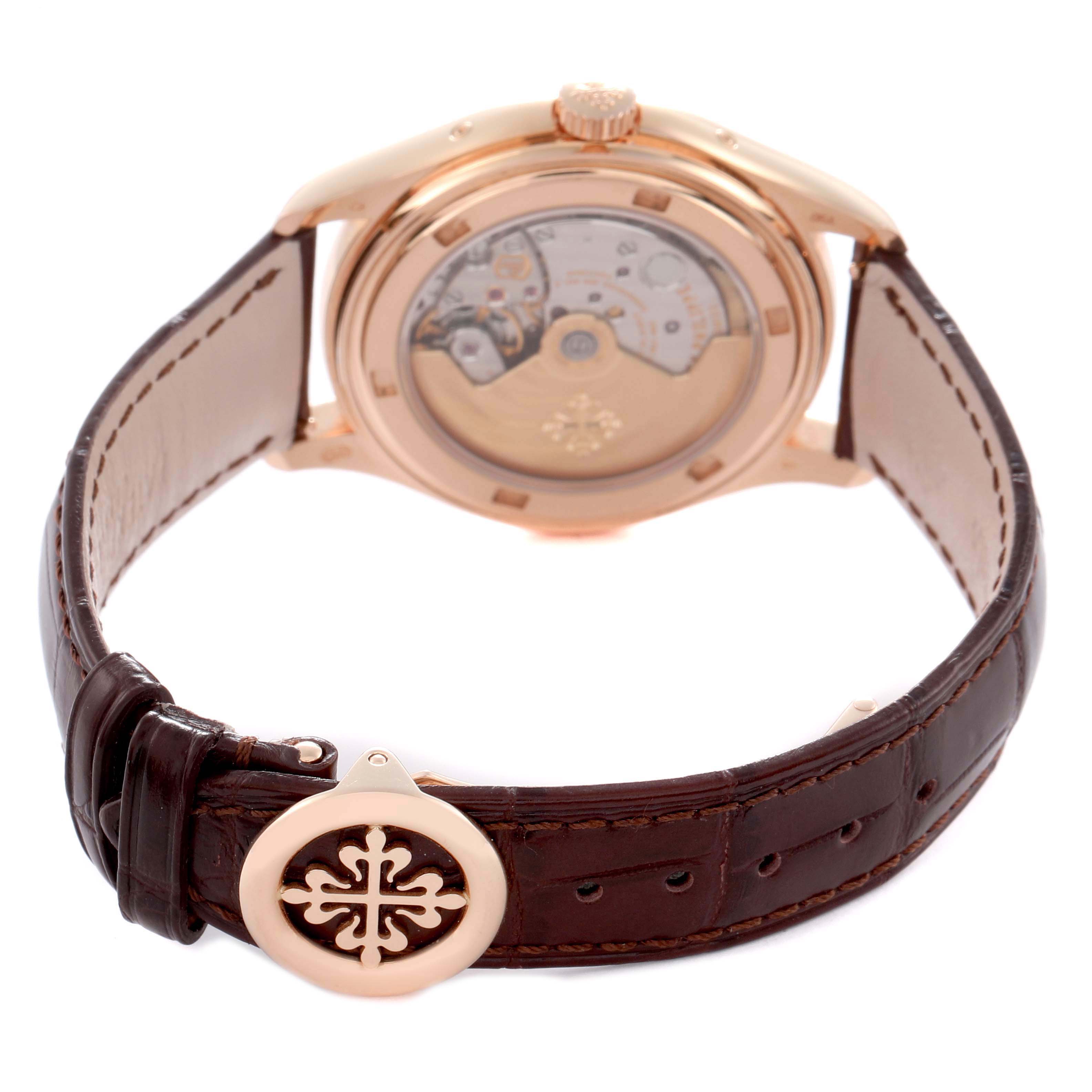 The Patek Philippe Complications 5146R is shown from the rear, displaying its open case back and brown leather strap with the branded clasp in view.