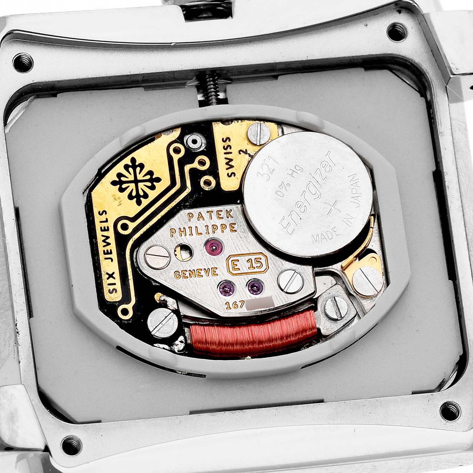 The image shows the internal movement of a Patek Philippe Twenty-4 4910/20G-001 Women's White Gold Black Dial watch, focused on the mechanism and battery.