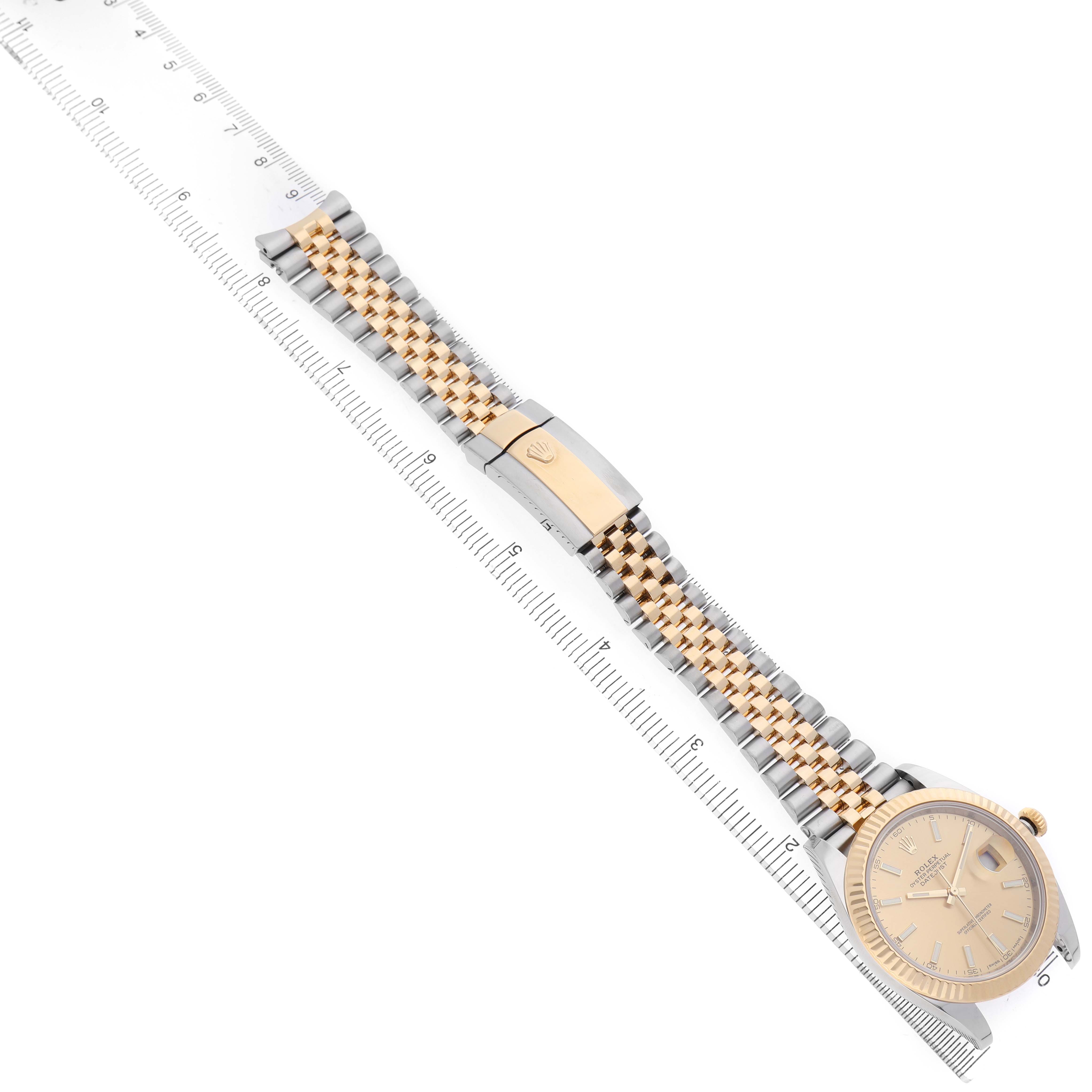 The Rolex Datejust 41 126333 Men's Steel and Gold (two tone) Champagne Dial watch is displayed from an overhead angle, showing its gold and silver bracelet and clasp, alongside a ruler.