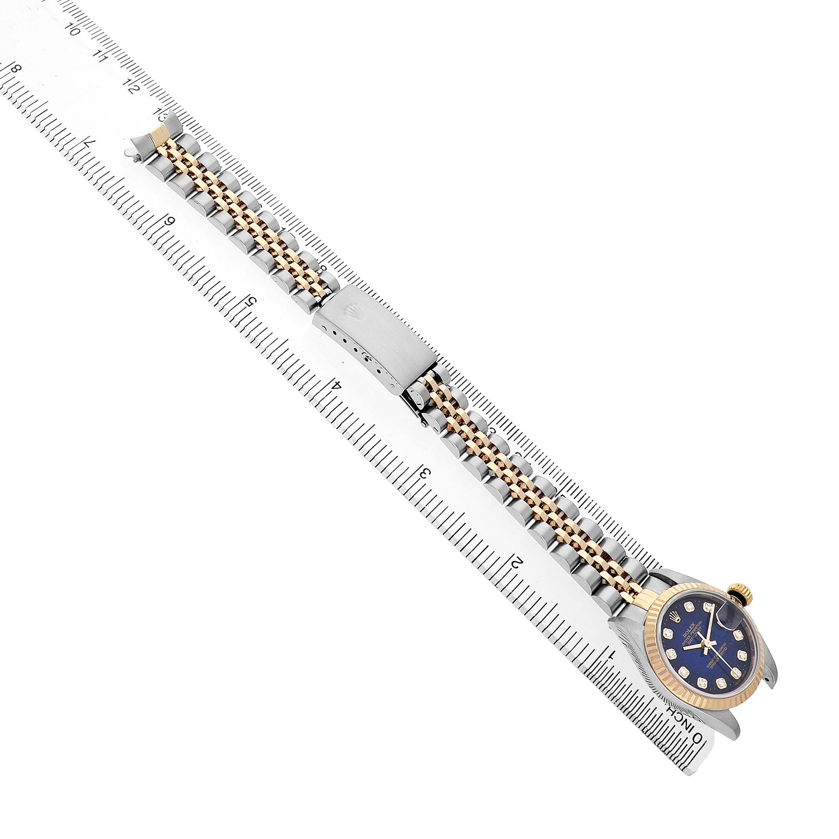 The image shows a Rolex Datejust 79173 Women's Steel and Gold (two tone) Blue Dial watch laid flat with its two-tone bracelet and clasp visible, next to a ruler.