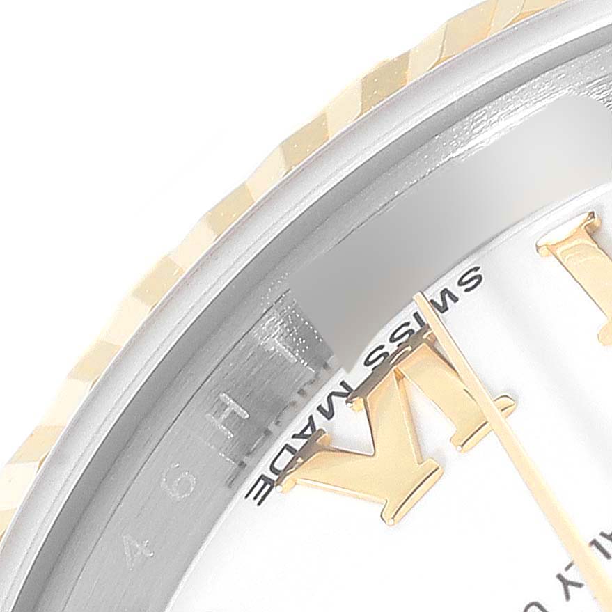 This close-up angle of the Rolex Datejust 179173 Women's Steel and Gold (two tone) White Dial 179173 Women's Steel and Gold (two tone) White Dial watch shows part of the fluted bezel, dial, and watch hands.