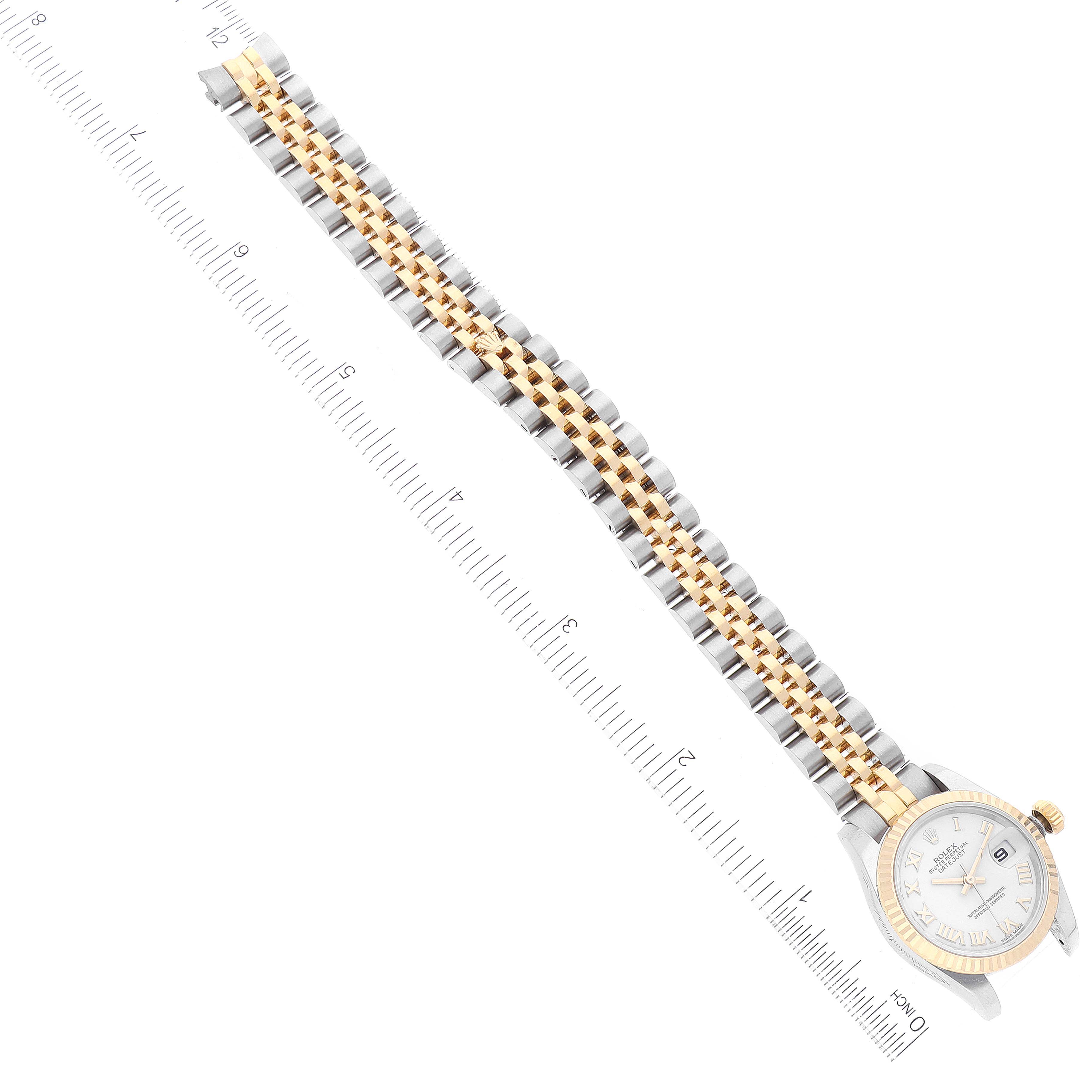 The Rolex Datejust 179173 Women's Steel and Gold (two tone) White Dial 179173 Women's Steel and Gold (two tone) White Dial watch is shown from a top view, displaying the face, entire band, and a measuring ruler beside it.