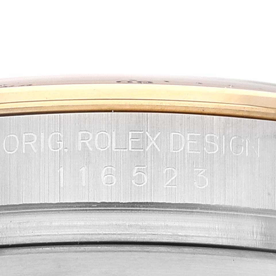 This close-up image shows the engraved side of a Rolex Daytona 116523 Men's Steel and Gold (two tone) Grey Dial 116523 Men's Steel and Gold (two tone) Grey Dial watch case, including the model number 116523.